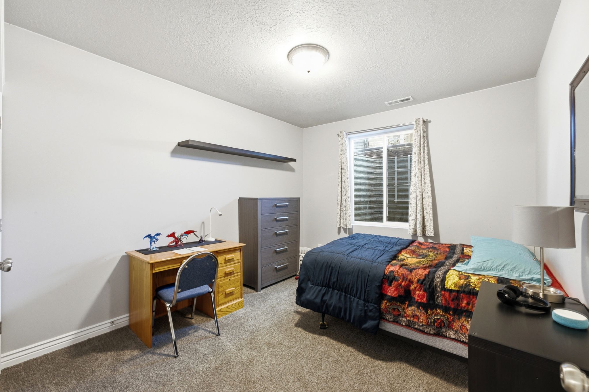Carpeted room featuring a single window, white walls, and a ceiling-mounted light fixture