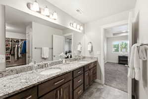 Dual vanity with granite countertop, undermount sinks, and dark wood-finish cabinetry