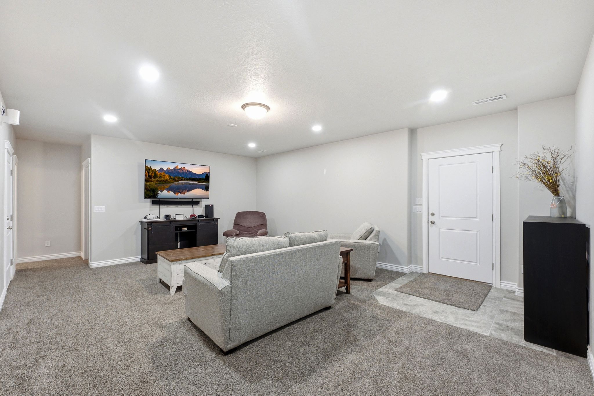 Spacious room with light gray walls and recessed lighting