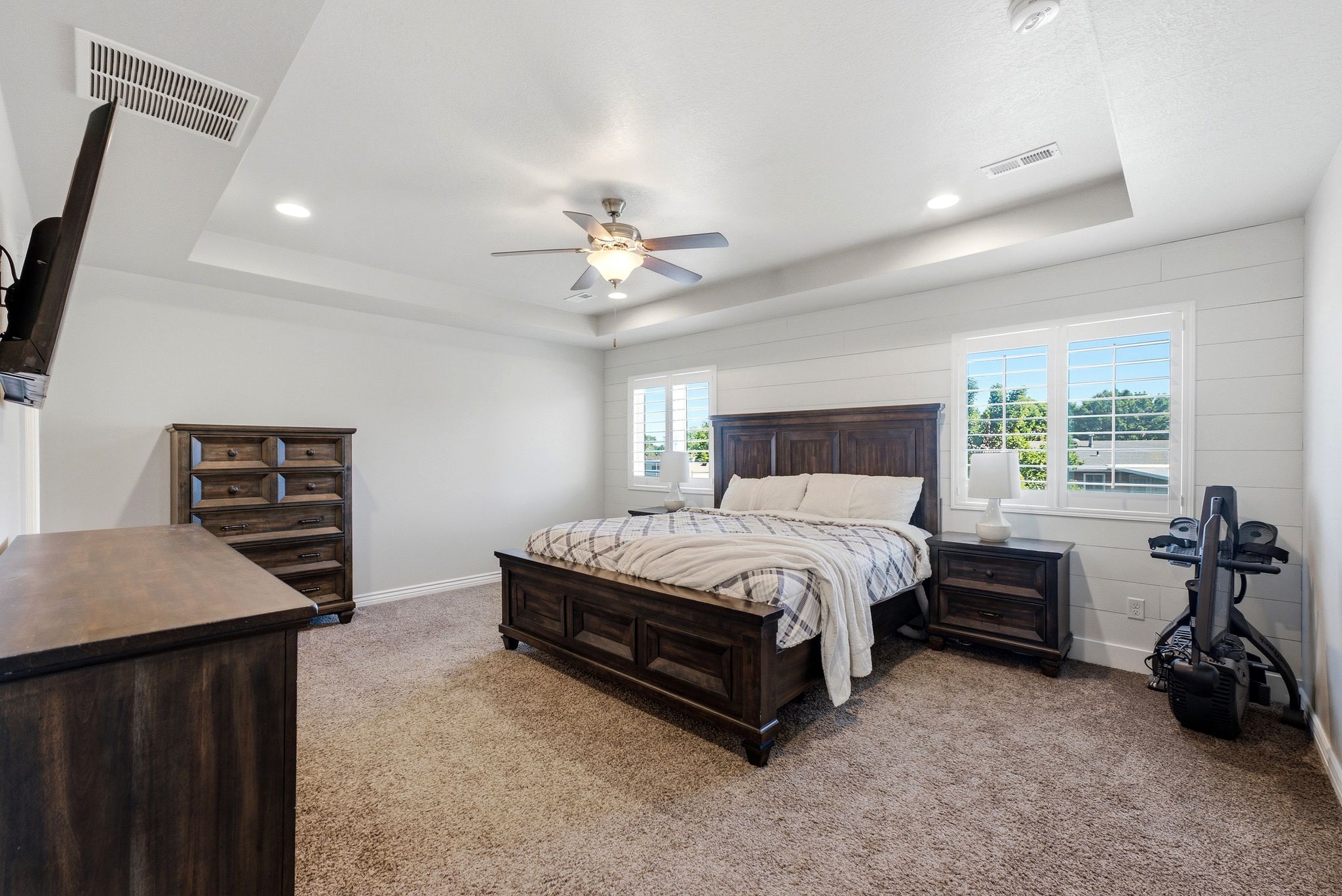 Spacious room featuring a tray ceiling with recessed lighting, a ceiling fan, and light-colored carpeting