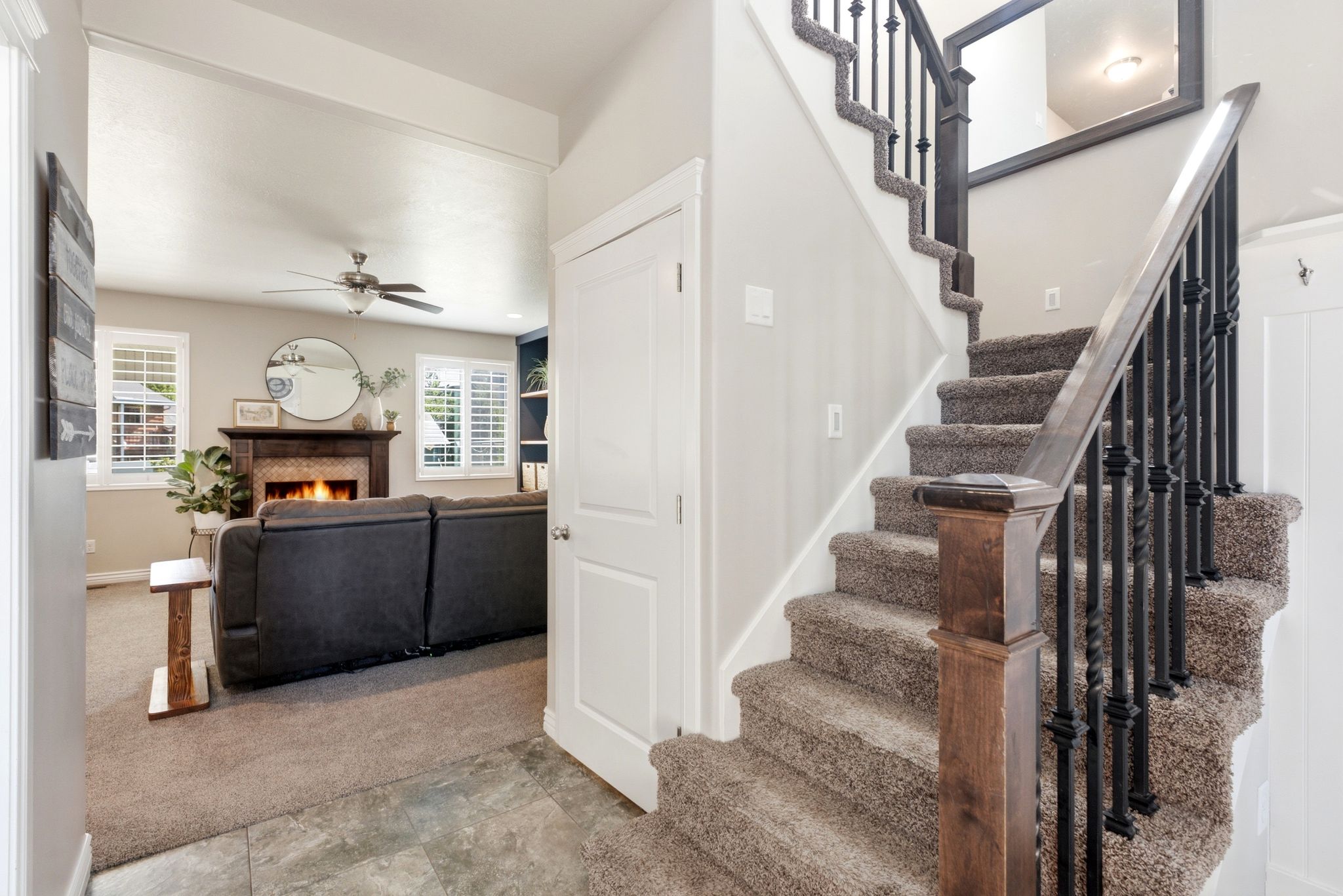 Carpeted staircase with black wrought iron balusters and a wood newel post