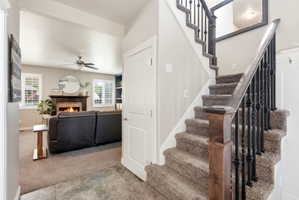 Carpeted staircase with black wrought iron balusters and a wood newel post