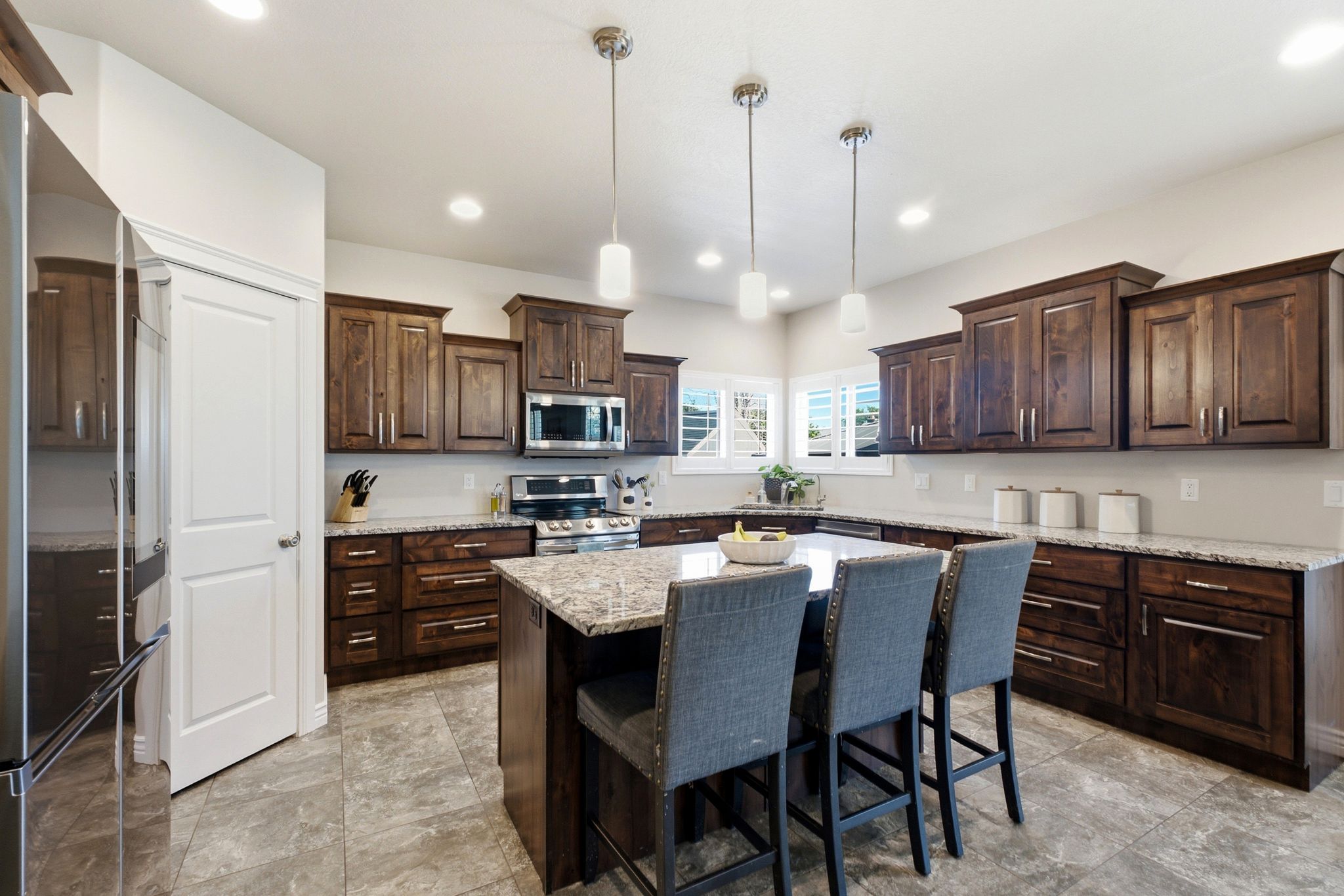 Kitchen featuring a large central island with seating, dark wood-finish cabinetry, light-toned countertops, and recessed lighting