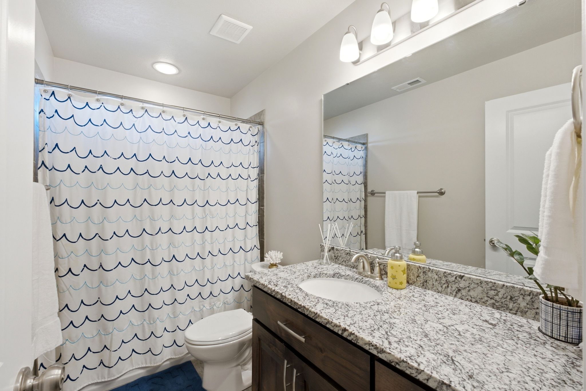Bathroom featuring a vanity with a light-toned speckled countertop, an undermount sink, and a large wall-mounted mirror