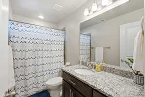 Bathroom featuring a vanity with a light-toned speckled countertop, an undermount sink, and a large wall-mounted mirror