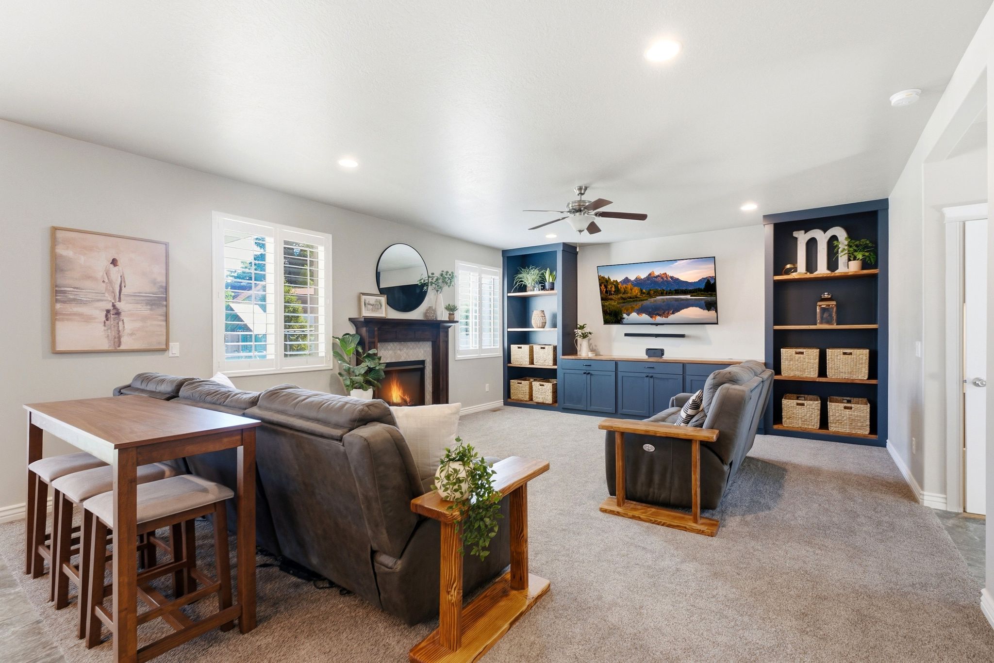 Spacious living area featuring a fireplace with a dark wood mantel, built-in shelving, and light-colored walls