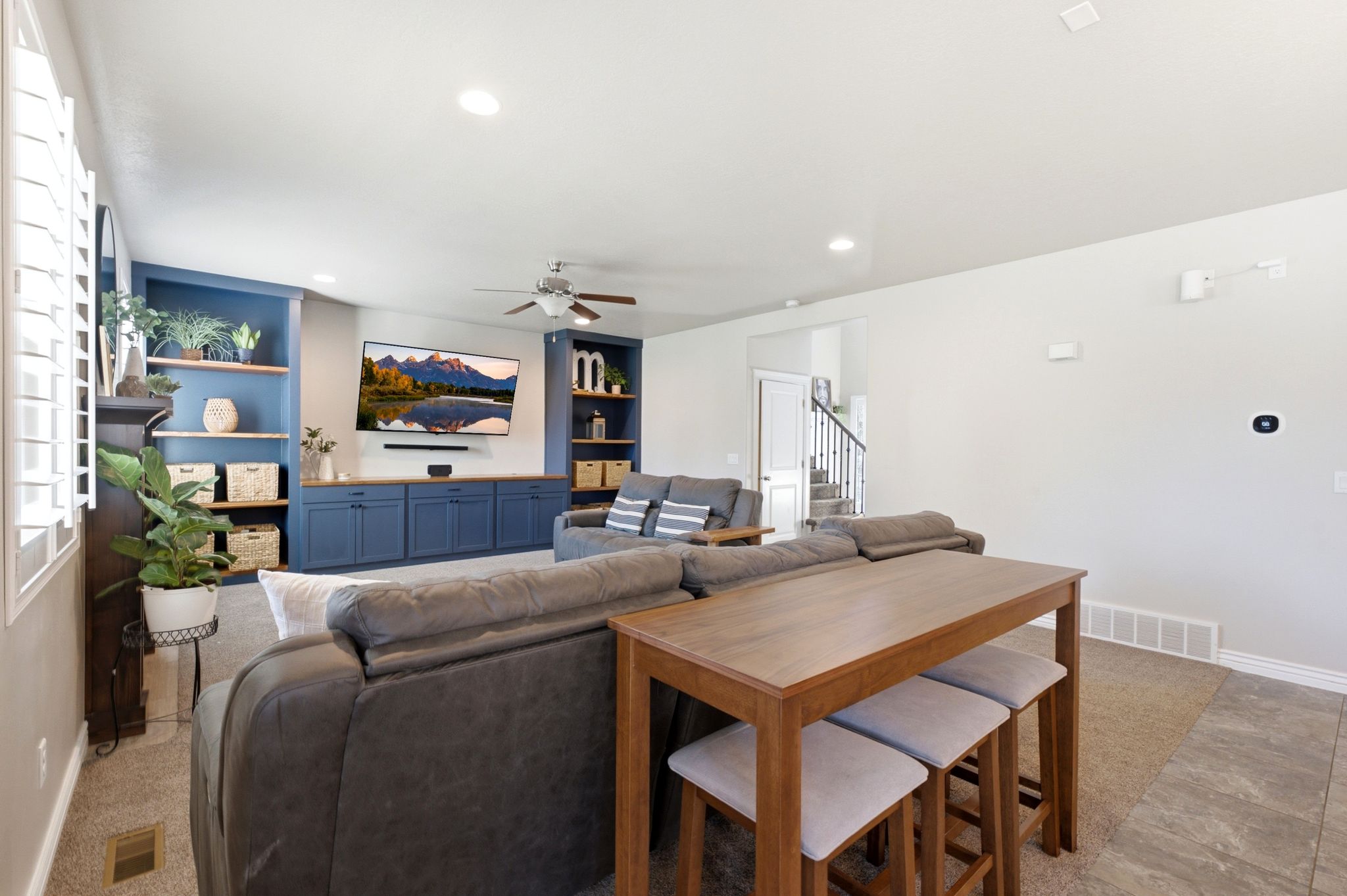Open-concept living area featuring a custom built-in entertainment center with blue cabinetry and wood-finish countertops