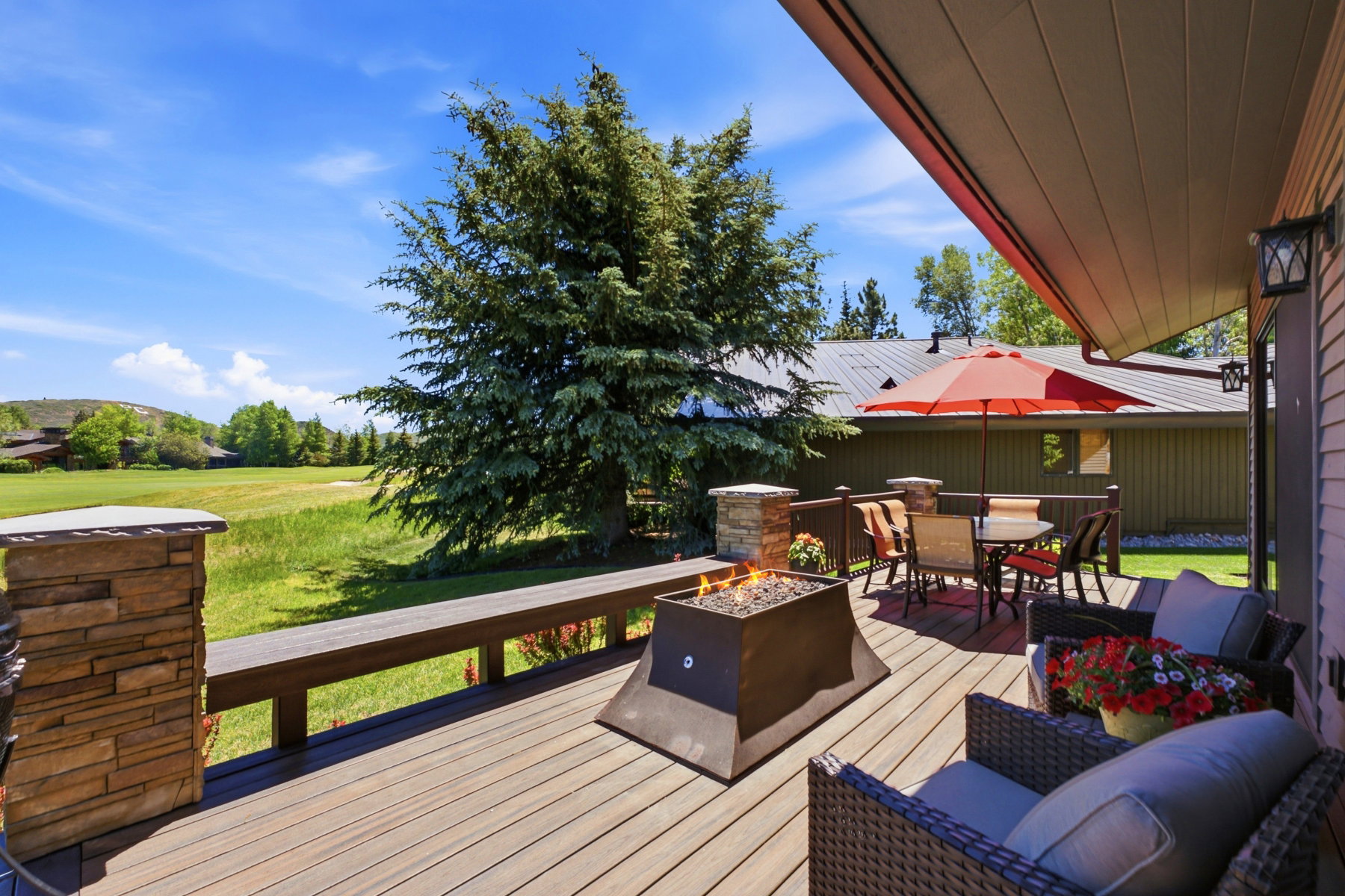 Expansive outdoor deck featuring wood-finish flooring and a built-in fire pit