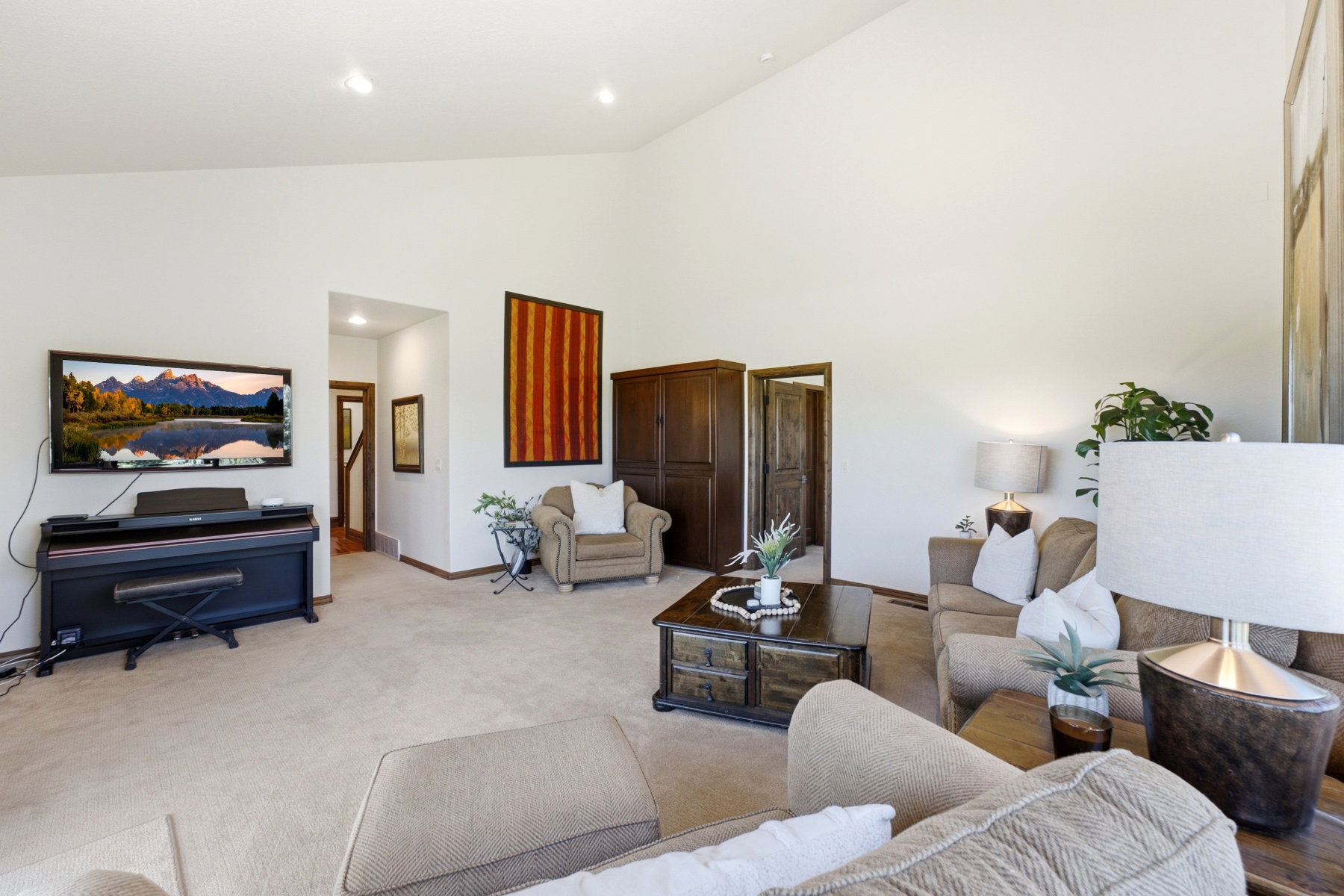 Spacious living area featuring a vaulted ceiling and neutral carpeting