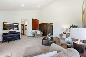 Spacious living area featuring a vaulted ceiling and neutral carpeting