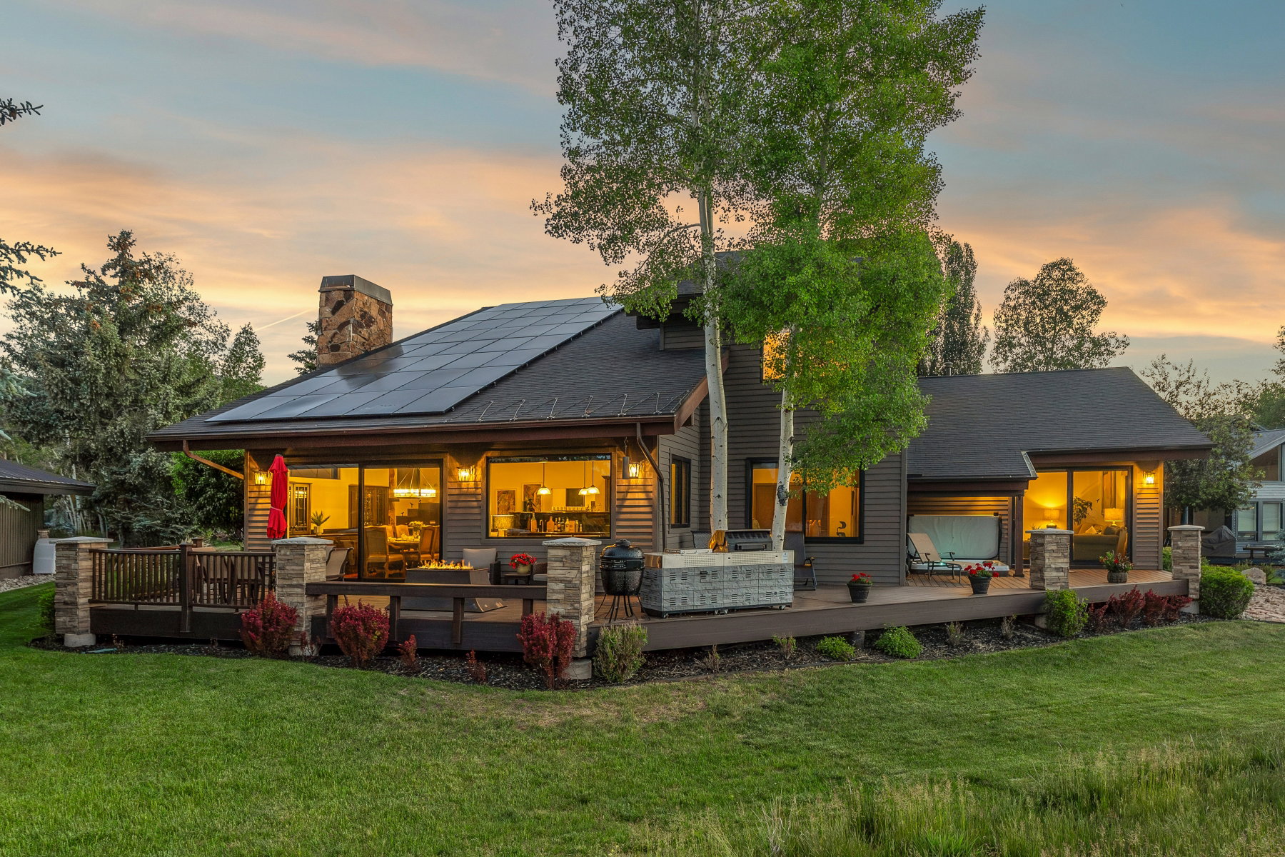 Expansive rear deck featuring a built-in spa, stone pillar accents, and a stone chimney