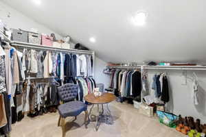 Spacious attic conversion featuring sloped ceilings, recessed lighting, wall-mounted clothing rods, and built-in shelving for organized storage