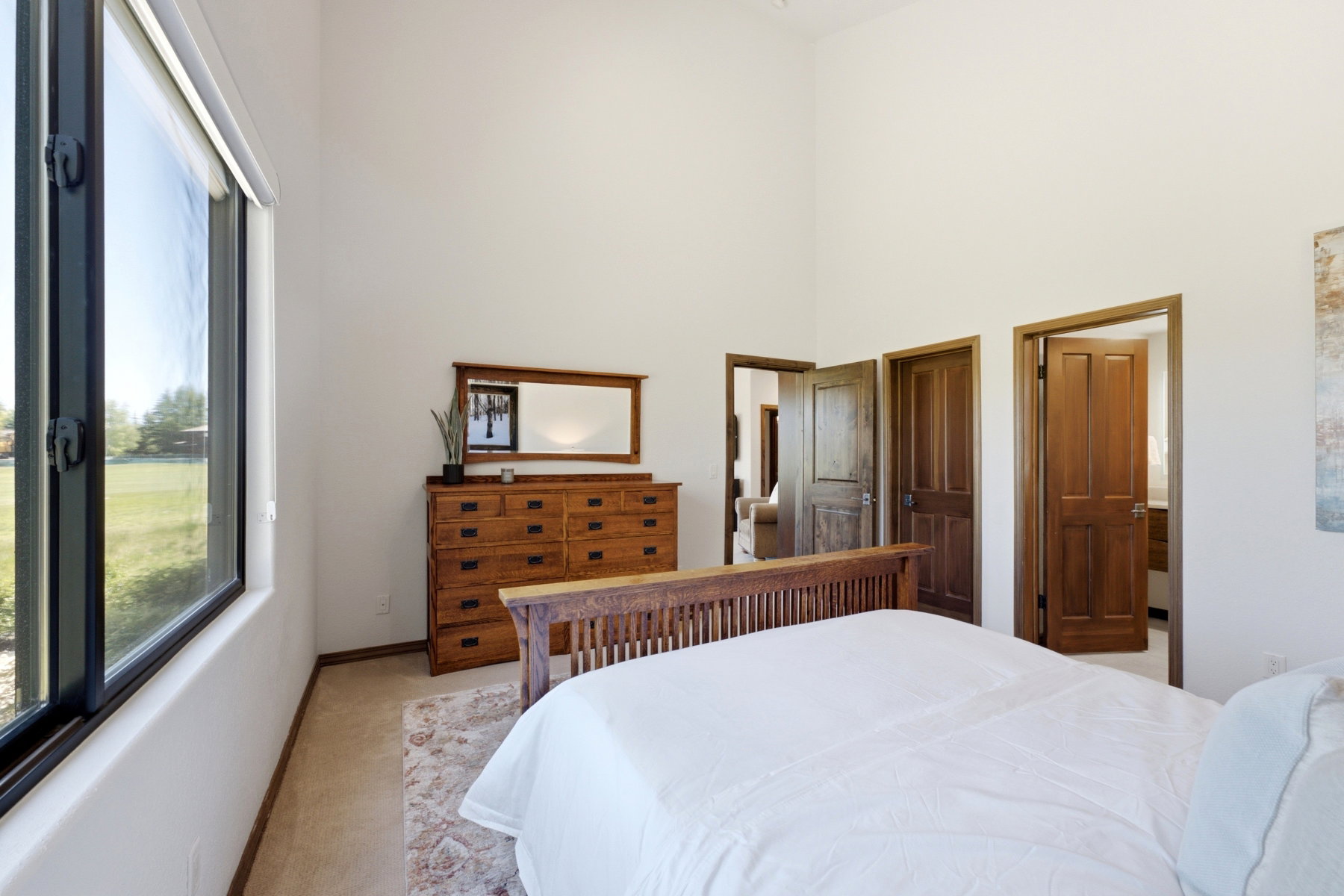 Expansive room featuring a large window, high ceilings, wood-finish doors, and light-toned flooring