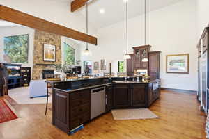 Open-concept living area featuring a kitchen island with dark cabinetry and a polished countertop, stainless steel appliances, and wood-finish flooring