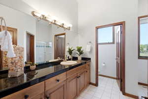 Double vanity with wood-finish cabinetry, black tile countertop, and undermount sinks