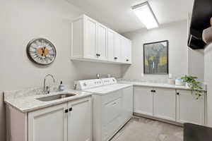 Laundry room with extensive white cabinetry, light-toned countertops, and a utility sink with a chrome faucet