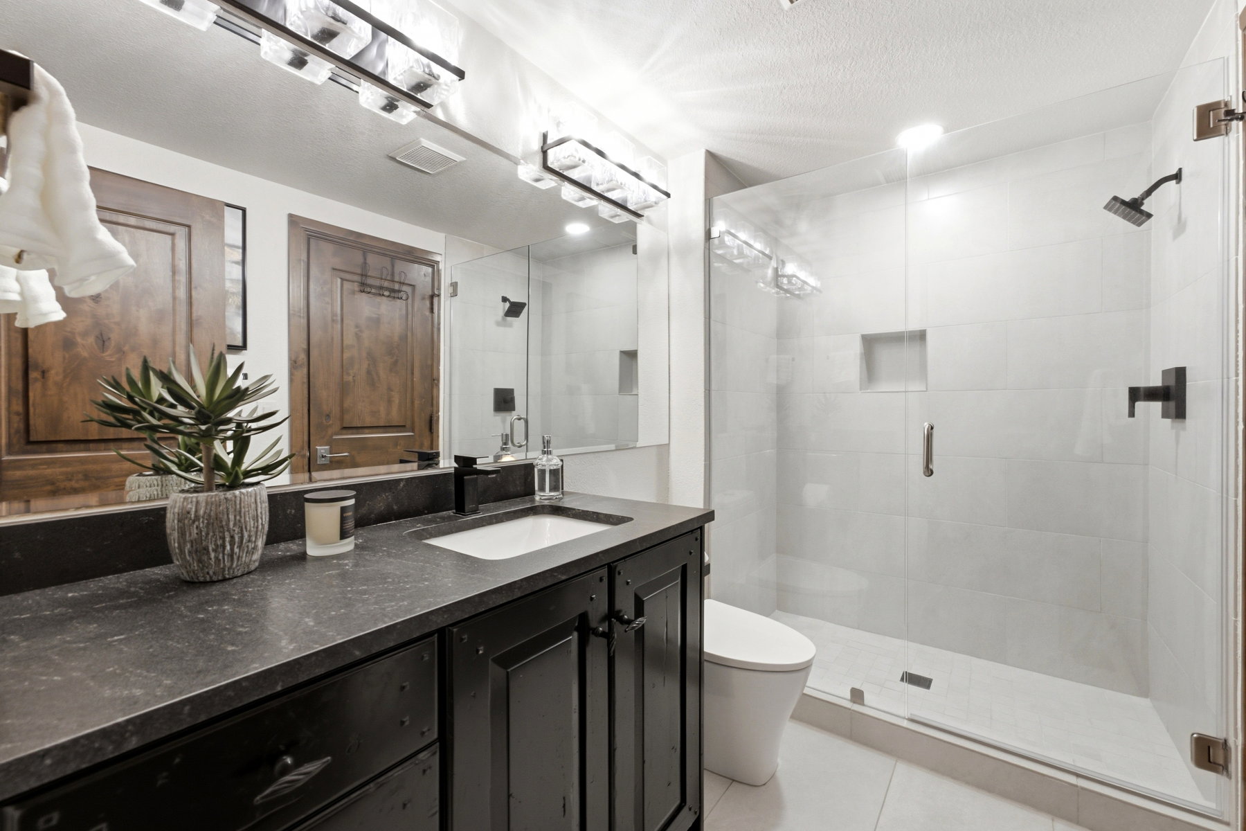 Modern bathroom featuring a single vanity with a dark countertop, a rectangular undermount sink, and a matte black faucet