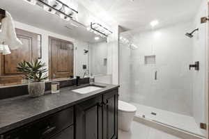 Modern bathroom featuring a single vanity with a dark countertop, a rectangular undermount sink, and a matte black faucet