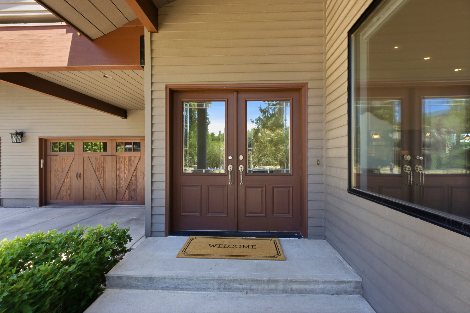Exterior facade featuring horizontal siding, a double entry door with glass inserts, and an expansive window