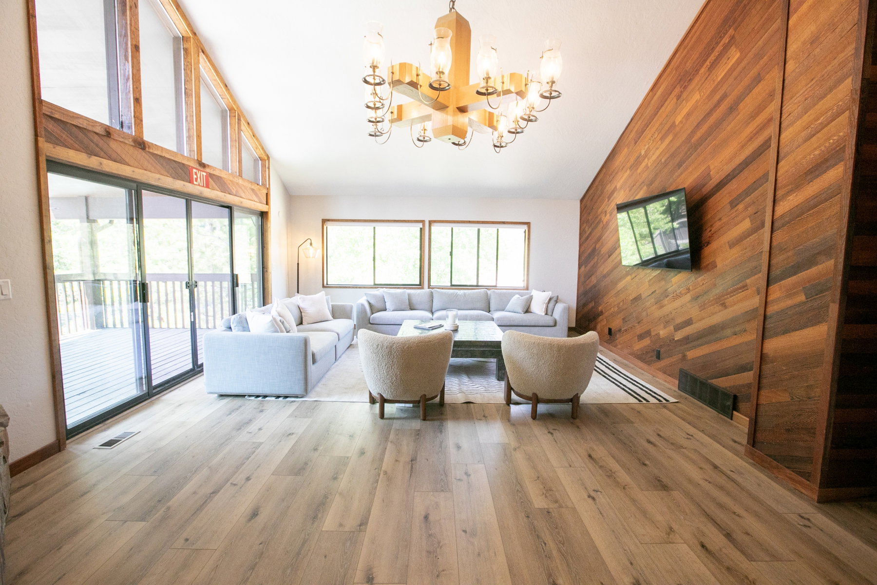 Spacious living area featuring light wood-finish flooring and a prominent wood-paneled accent wall