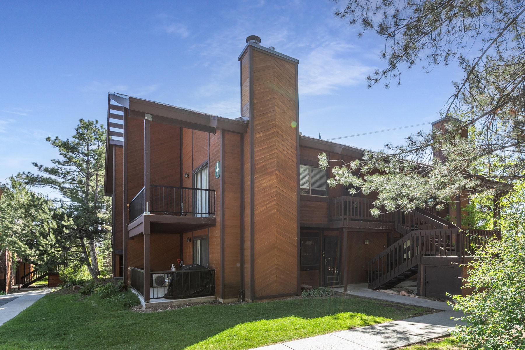 Multi-level exterior featuring wood-finish siding, a prominent brick chimney, and multiple balconies with dark railings