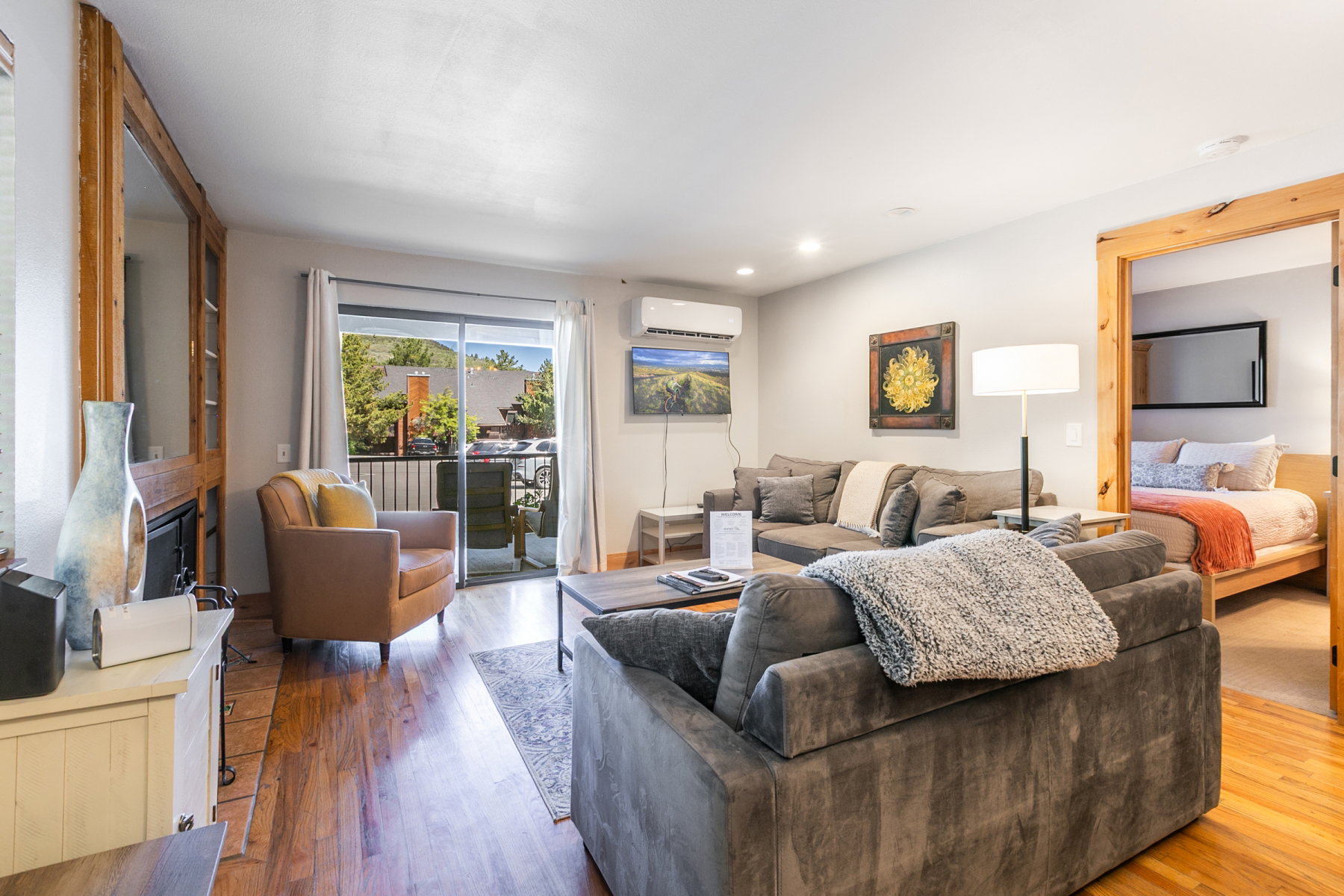 Living area with wood-finish flooring, recessed lighting, and a built-in fireplace featuring a wood surround