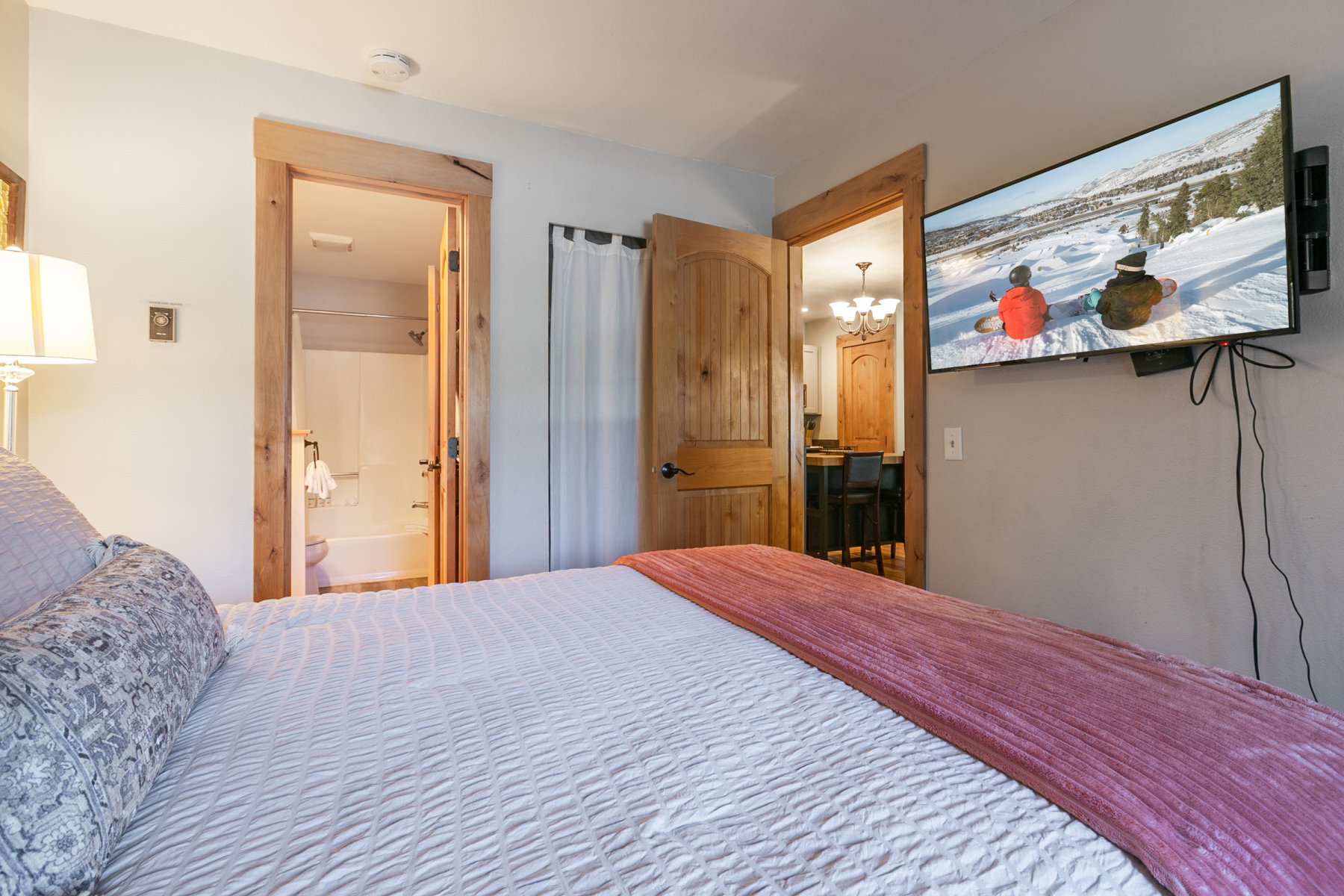 Bedroom featuring a wall-mounted television, wood-finish interior doors, and substantial wood door frames