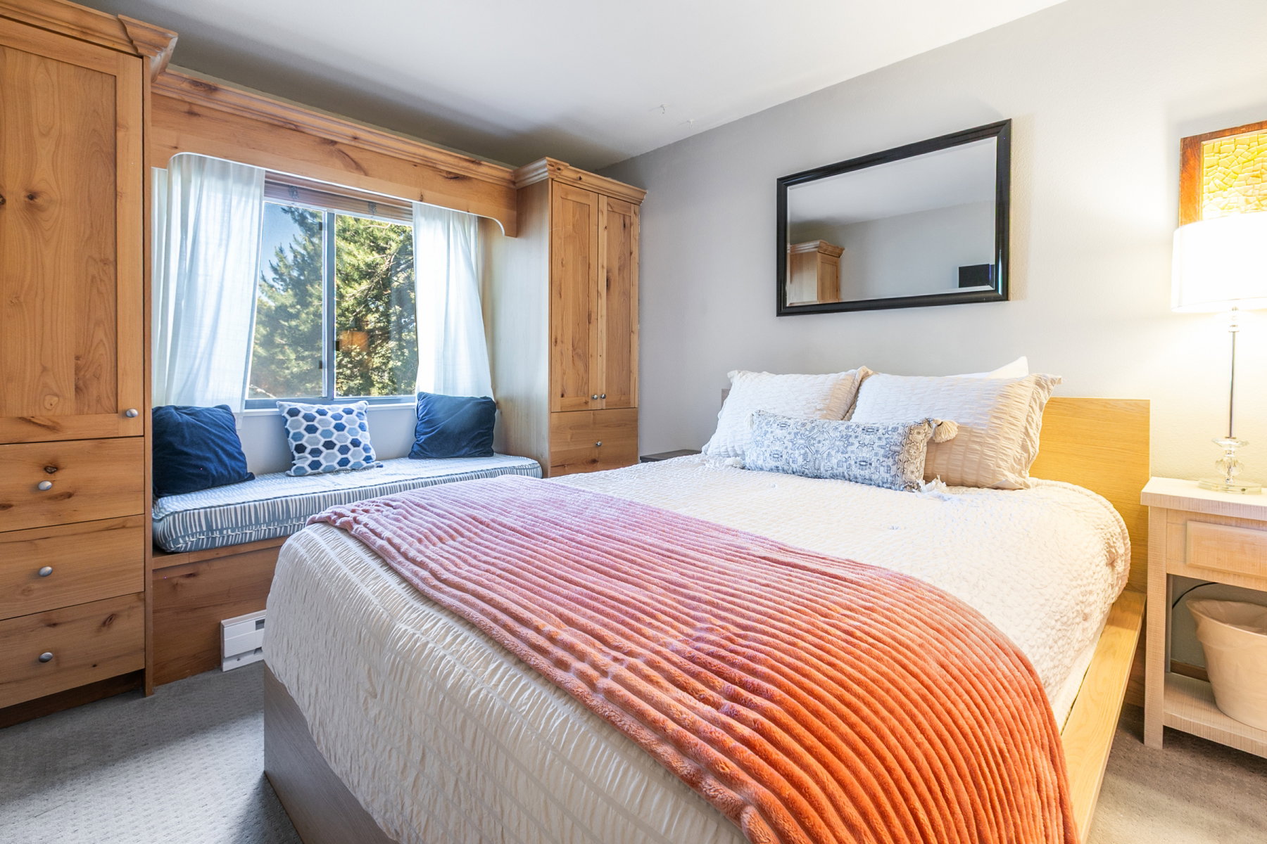 Integrated window seating with storage, flanked by built-in wood cabinetry, offers functional appeal