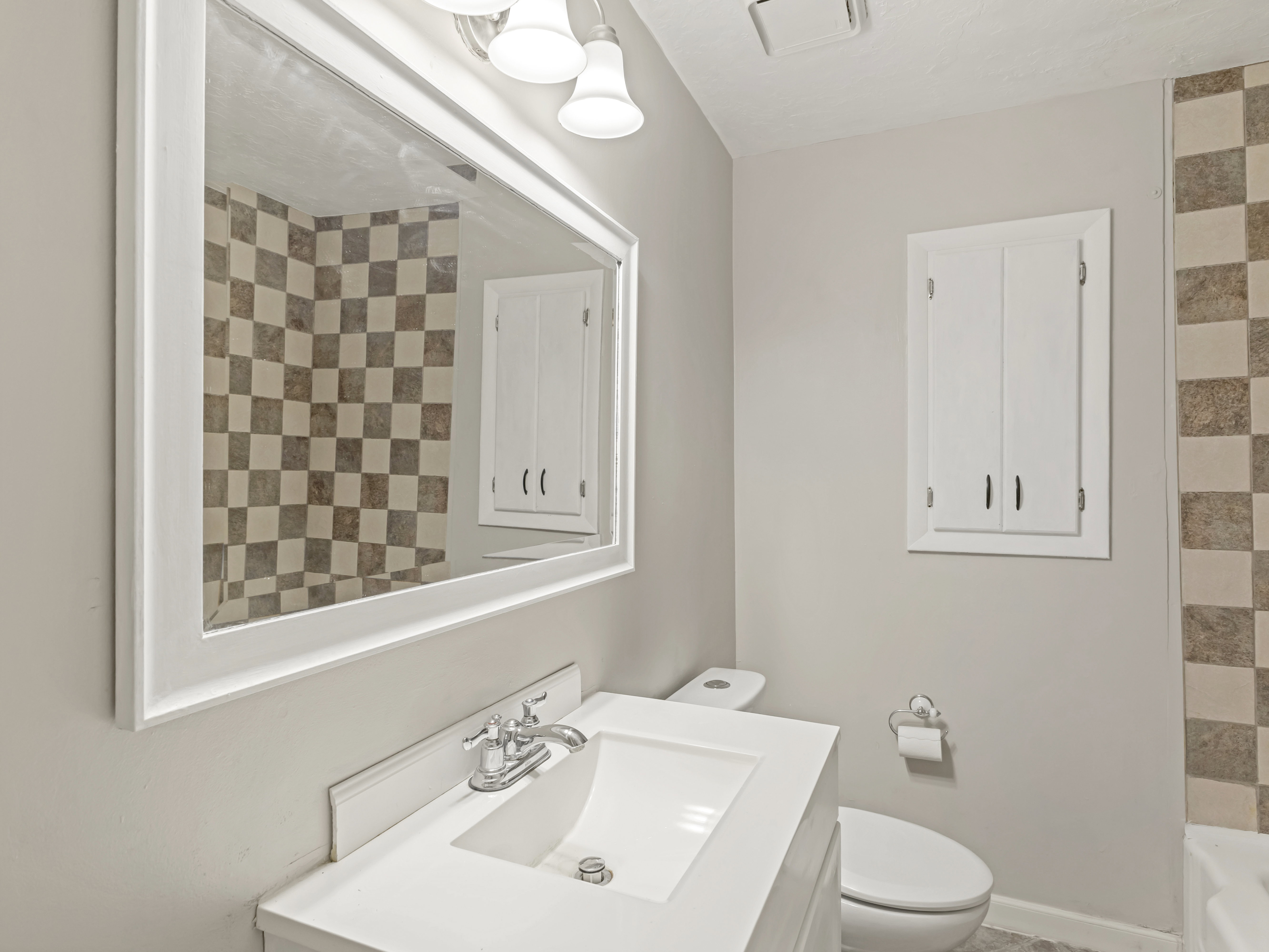 Bathroom featuring a white vanity with an integrated sink, chrome faucet, and a large framed mirror