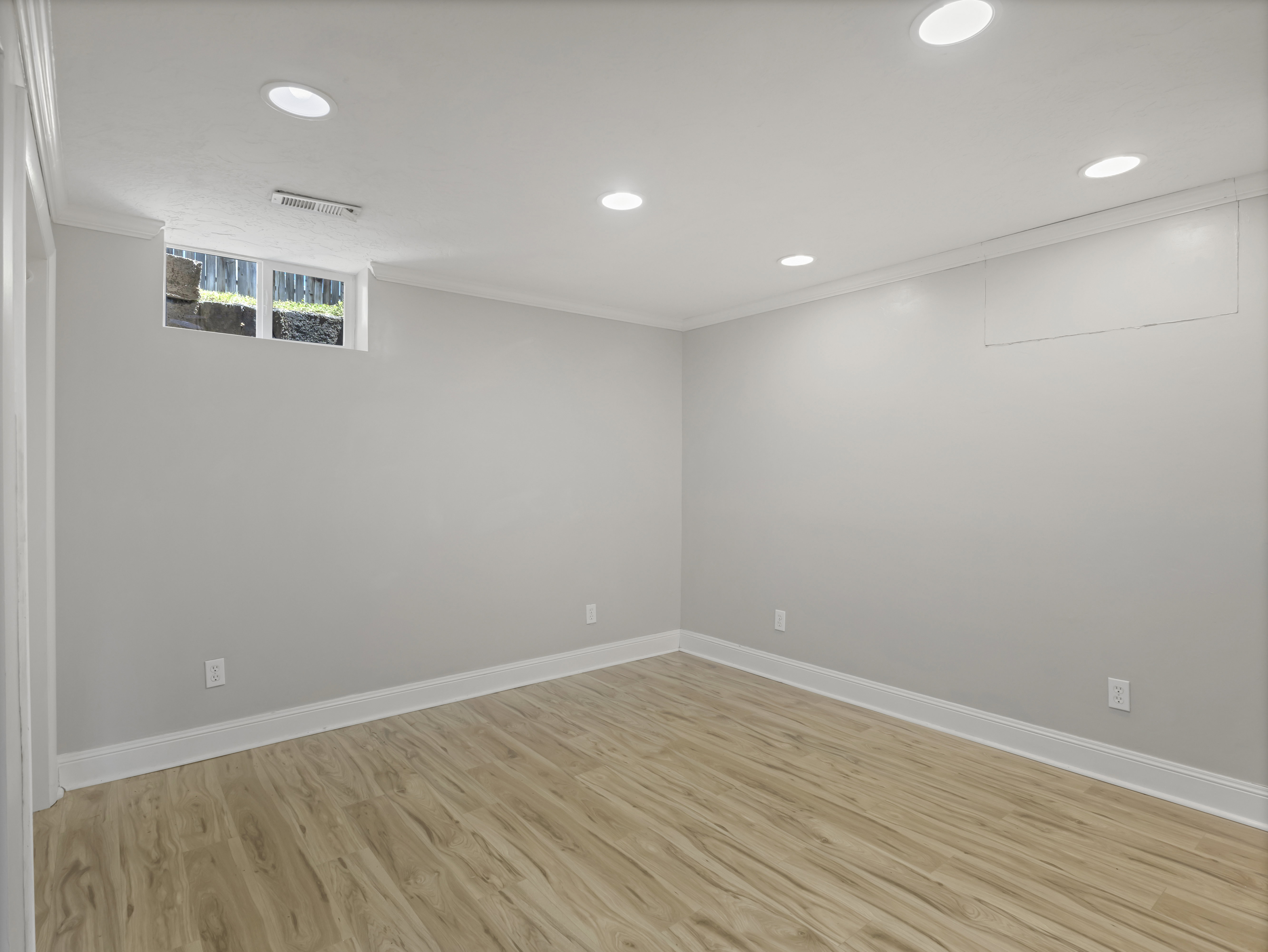 Spacious room featuring light wood-finish flooring, recessed lighting, and a neutral wall color