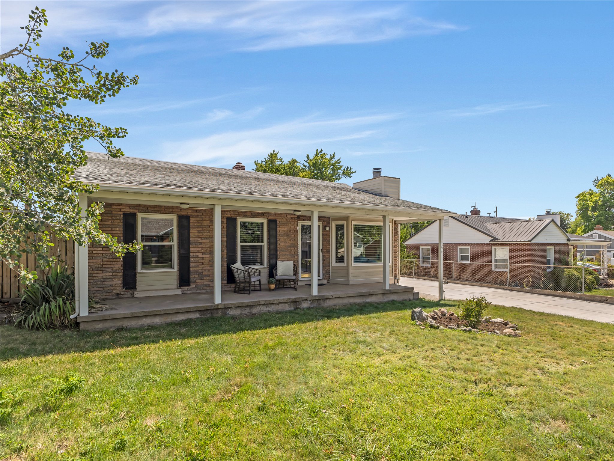 Brick exterior with a covered porch, featuring white support pillars and black window shutters