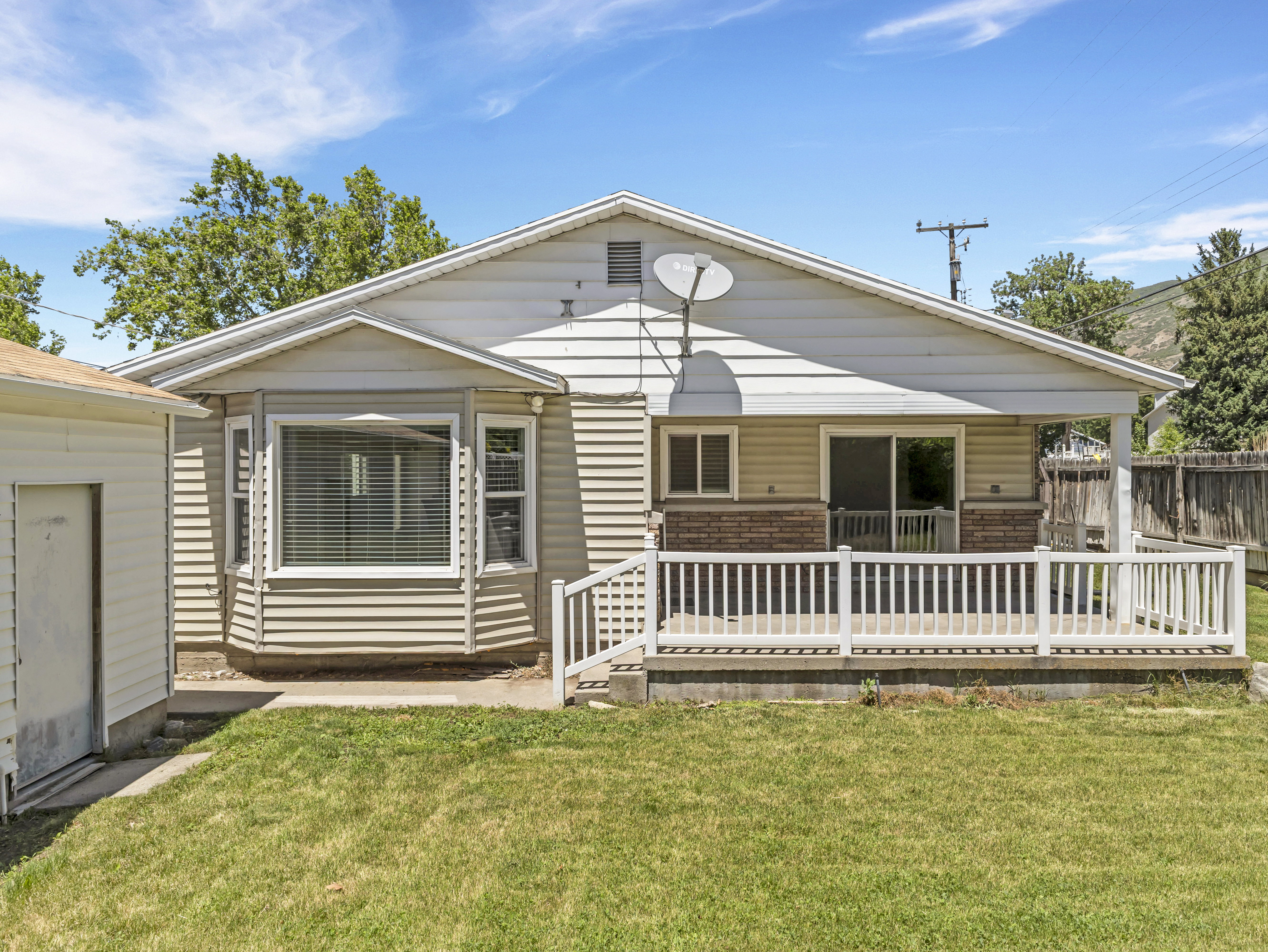 Rear exterior with light-colored horizontal siding and a covered deck
