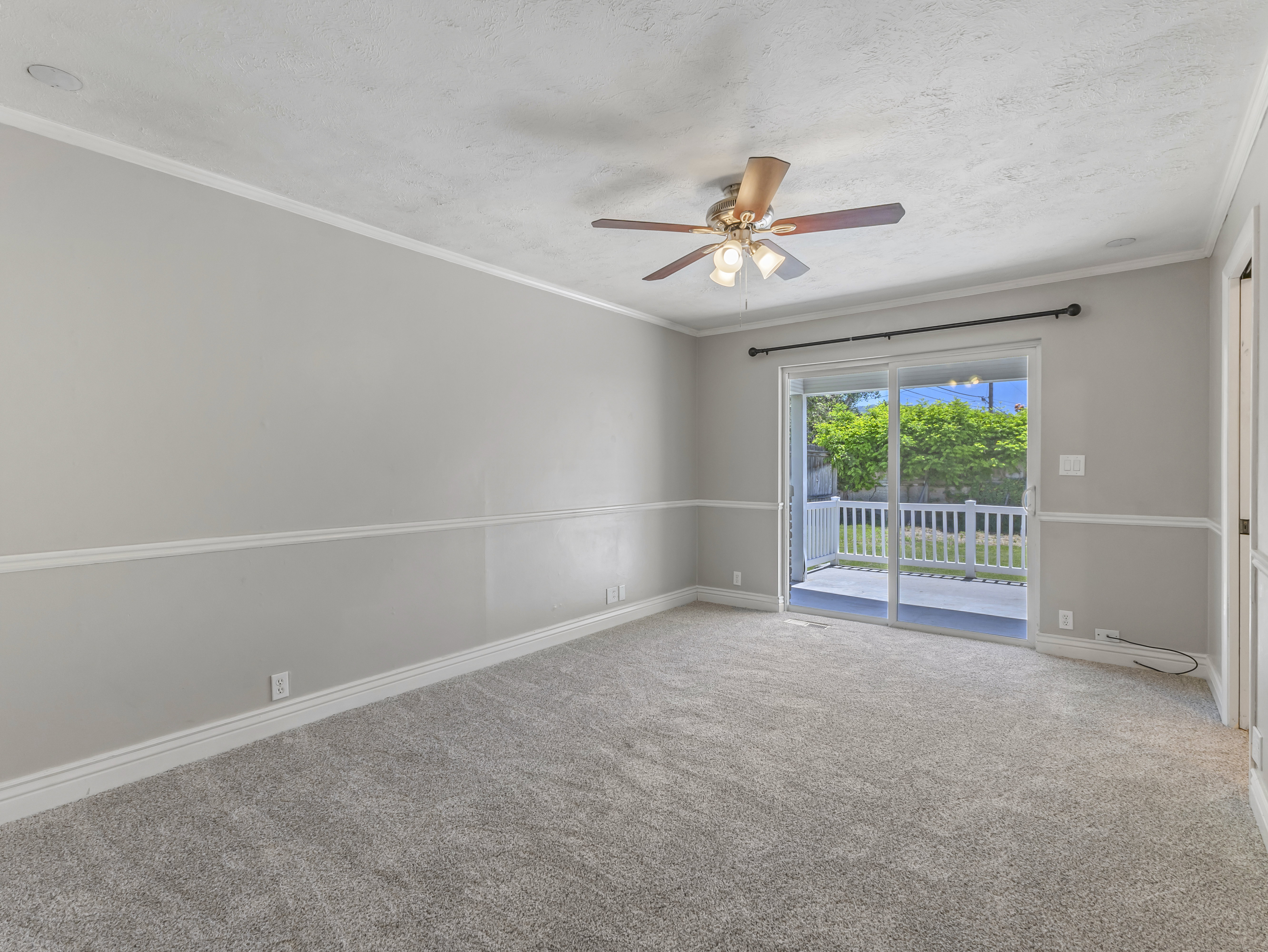 Carpeted interior space with a sliding glass door opening to an outdoor patio