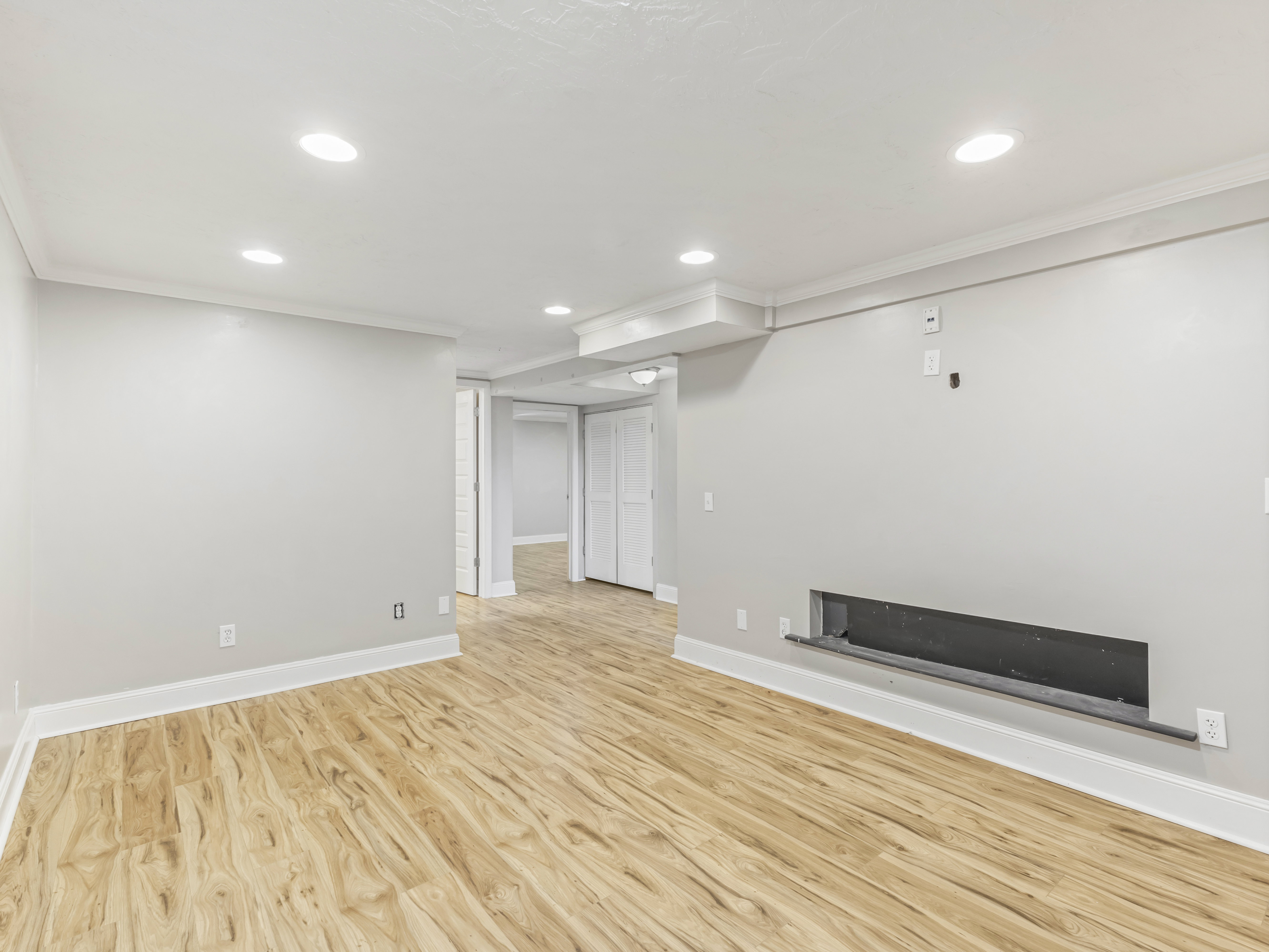 Spacious interior featuring wood-finish flooring, recessed lighting, crown molding, and a built-in linear fireplace opening