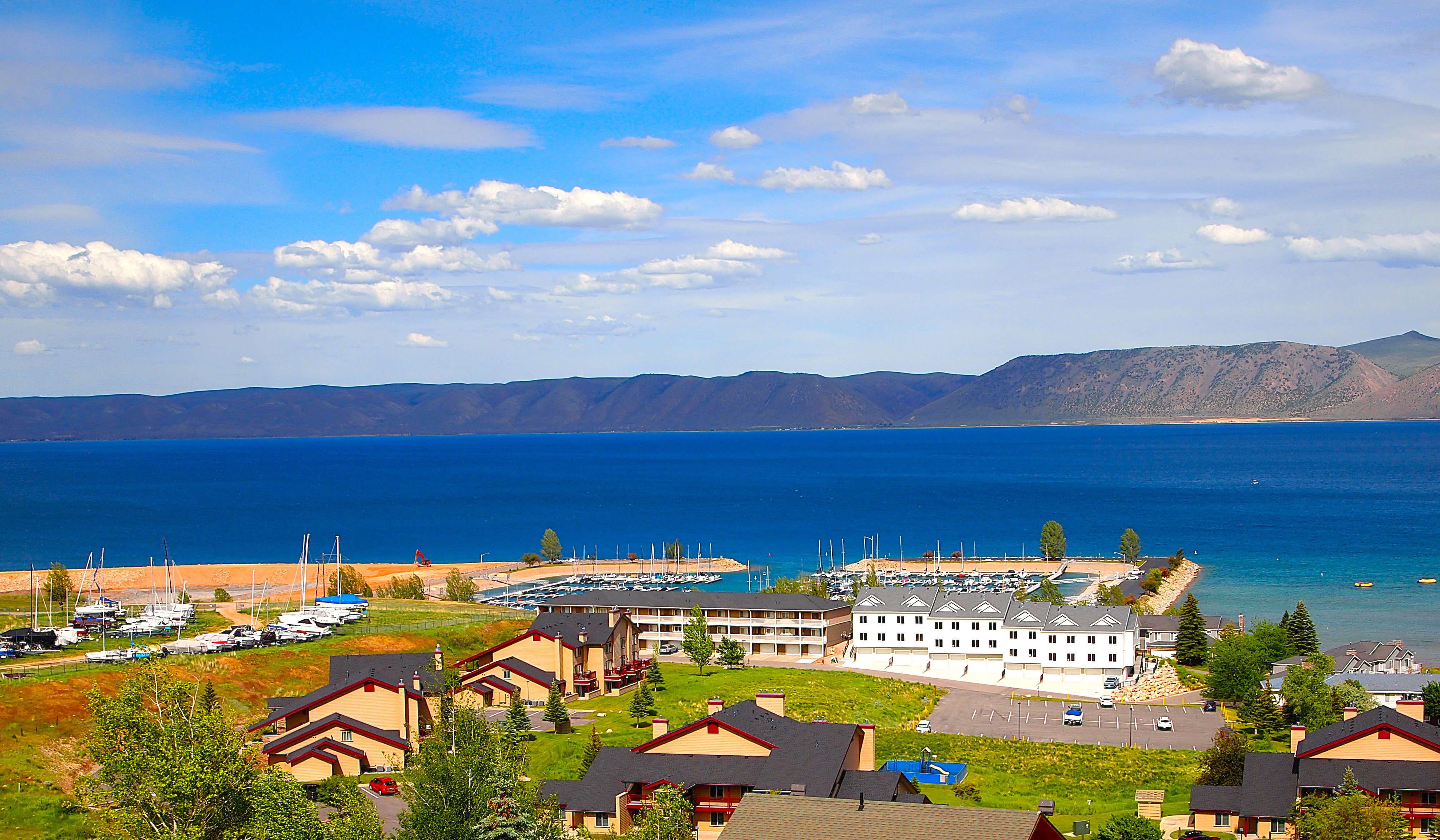 Expansive waterfront setting featuring a marina, distant mountains, and multiple residential structures