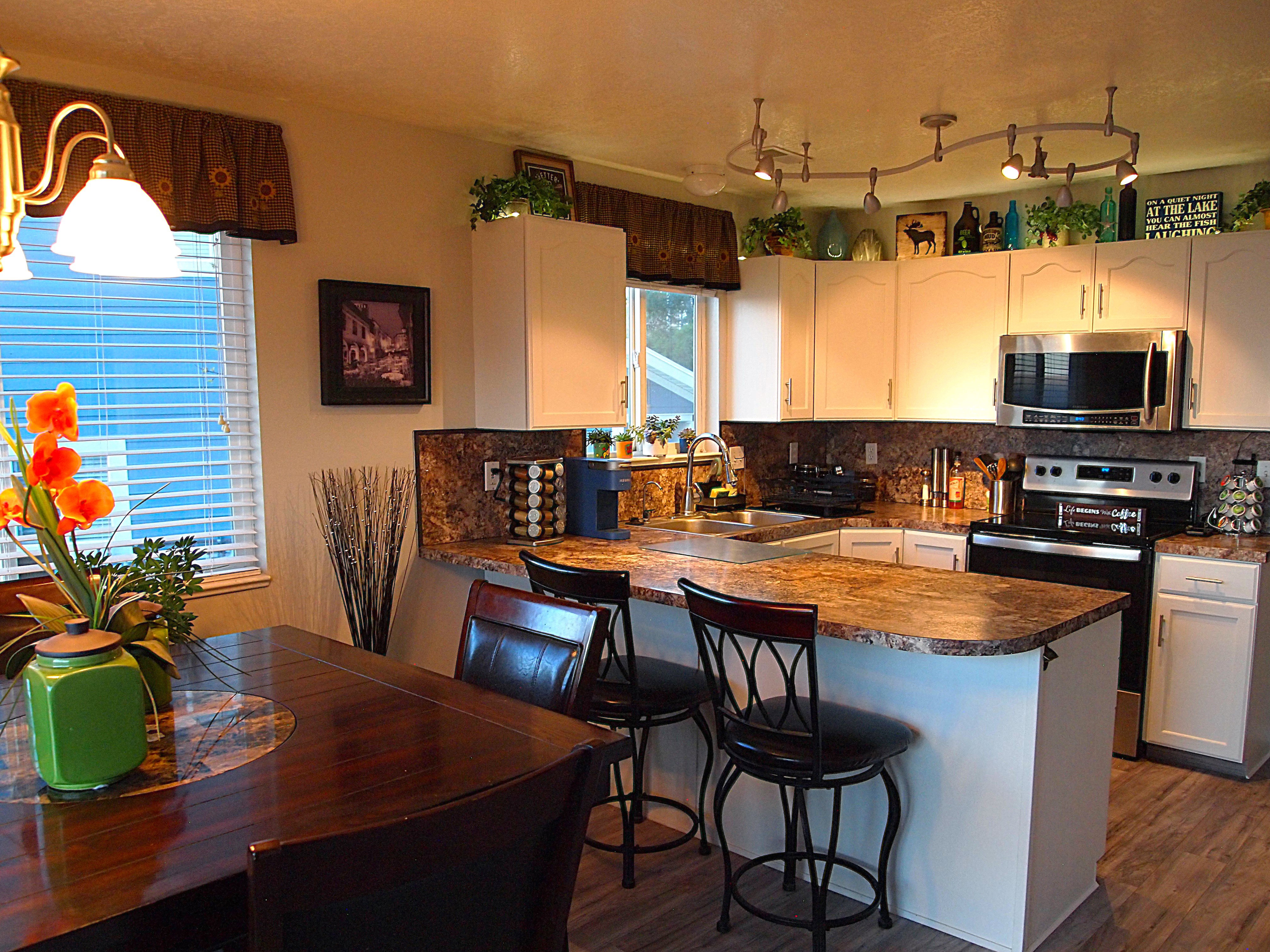 Kitchen featuring wood-finish flooring, white cabinetry, and granite-look countertops
