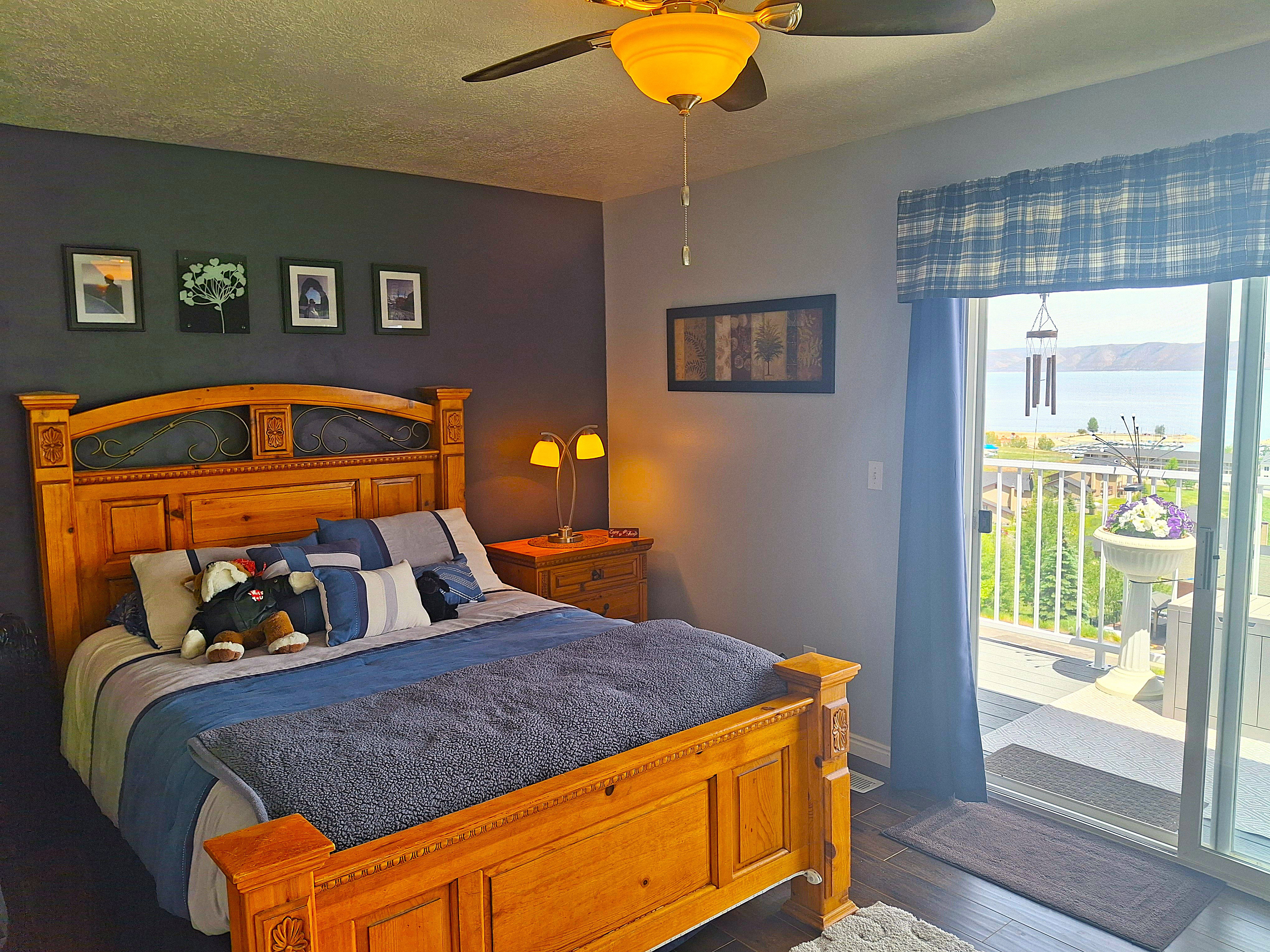 Bedroom with wood-finish flooring, ceiling fan, and sliding glass door access to an exterior deck