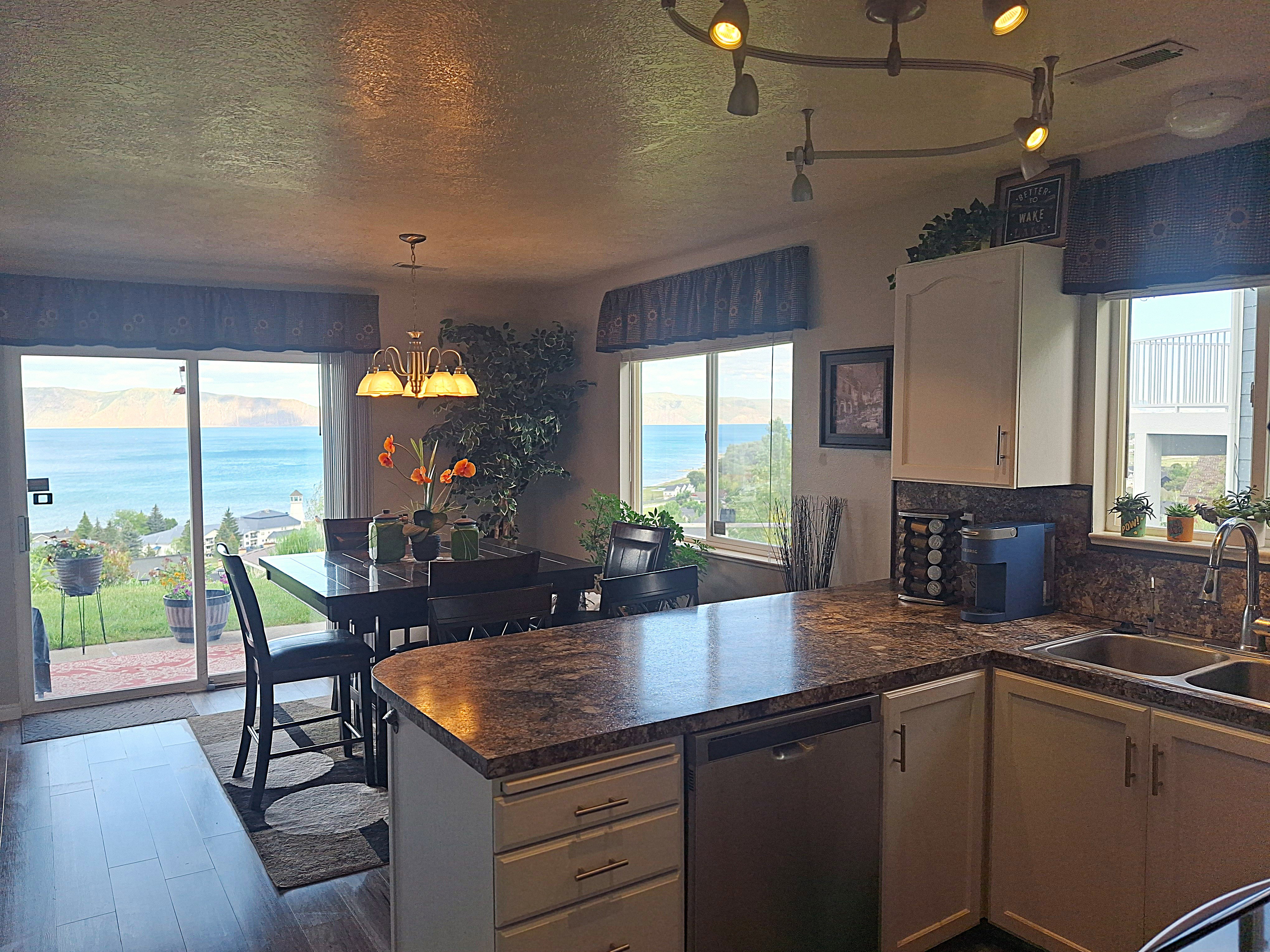 Kitchen and dining area featuring a sliding glass door and multiple windows showcasing a water backdrop