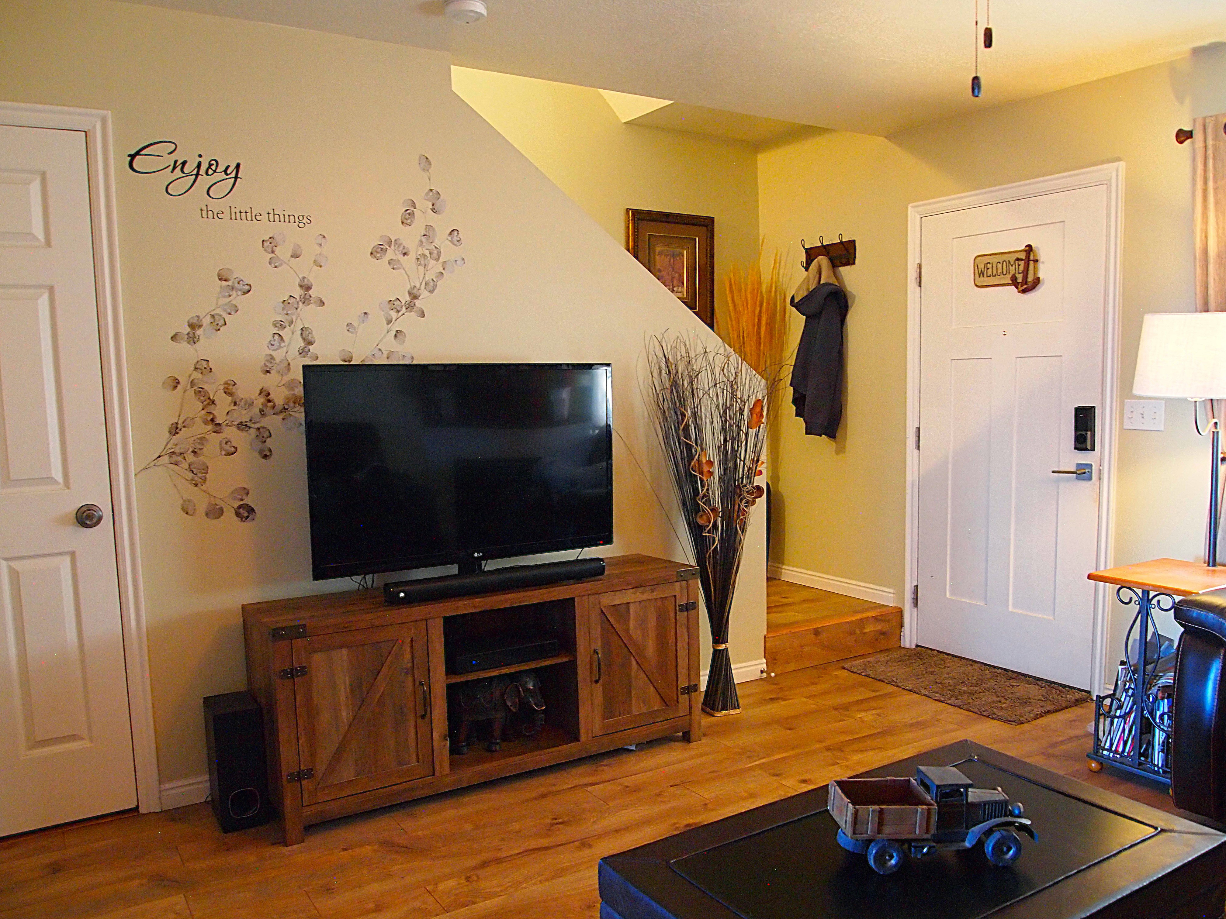 Warm interior space featuring wood-finish flooring, a paneled door, a staircase with wood treads, and light-toned walls