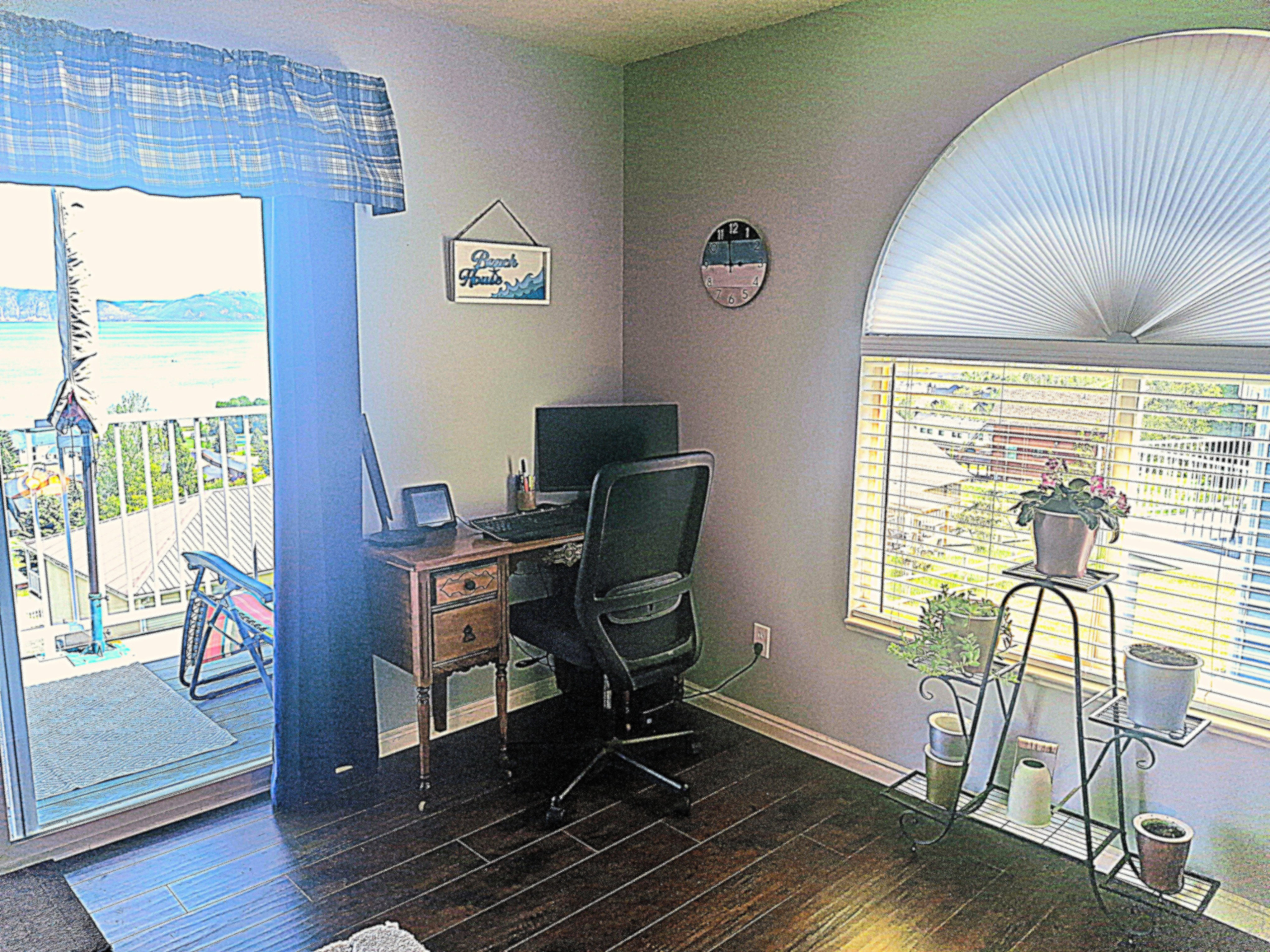 Interior room featuring wood-finish flooring, a sliding glass door leading to an outdoor balcony, and an arched window with pleated shades