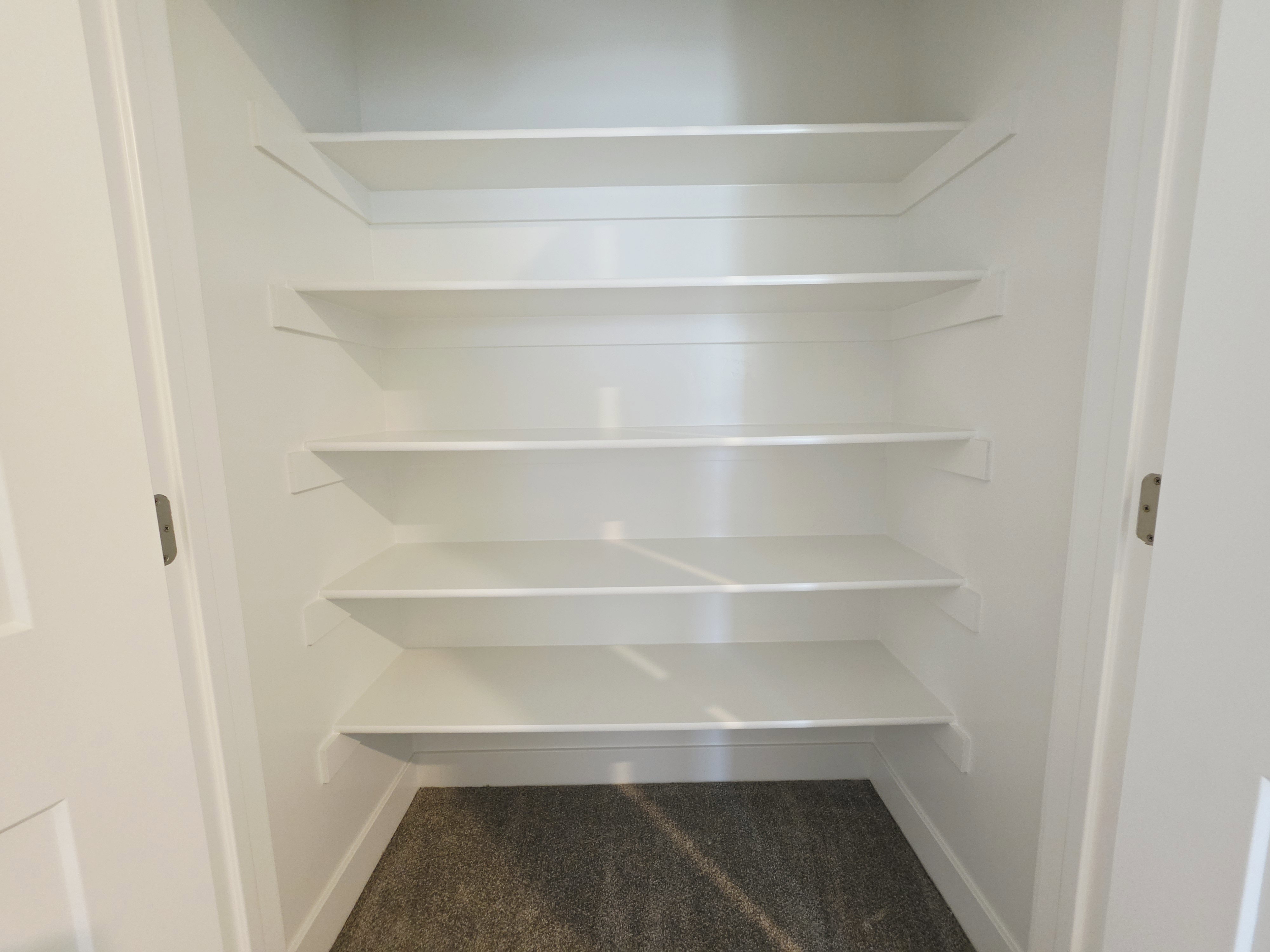 Built-in closet shelving with white finishes and a carpeted floor