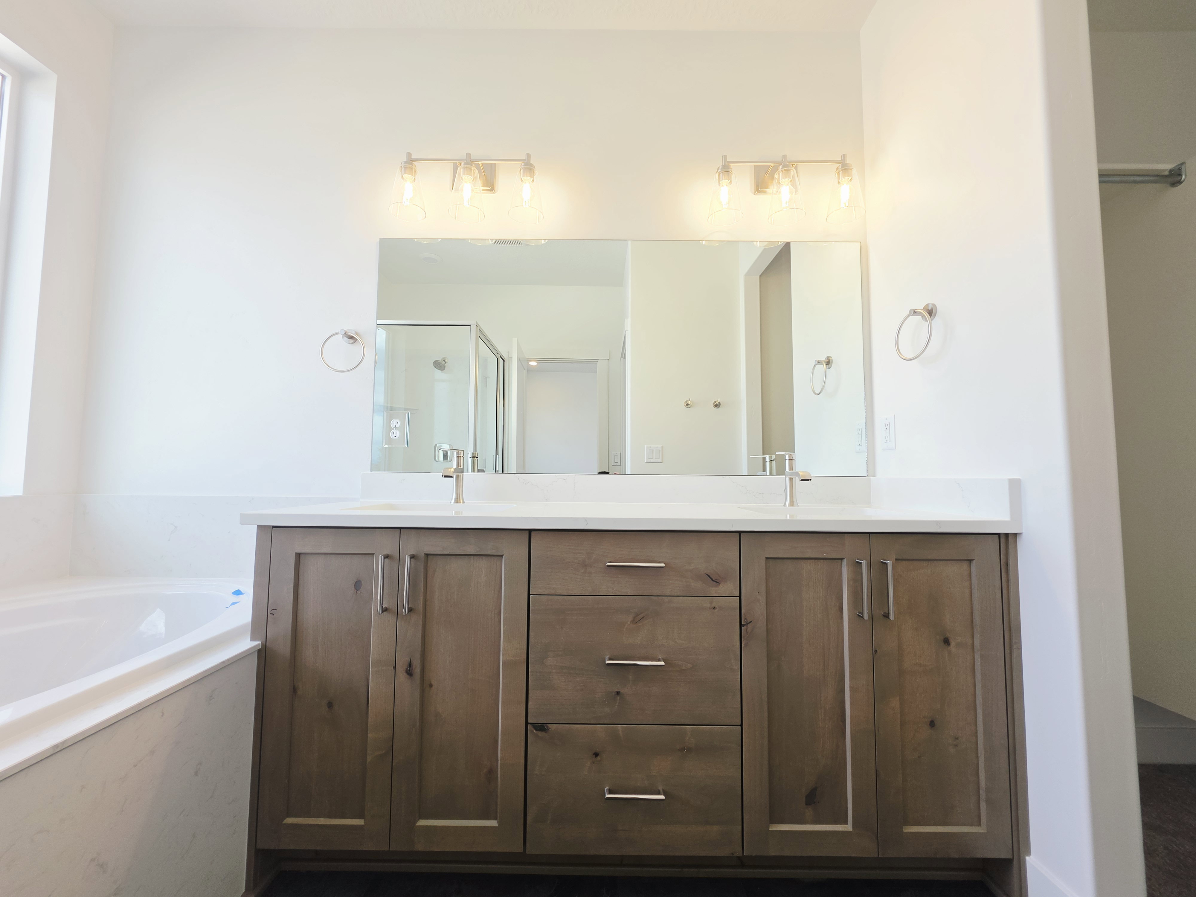Dual sink vanity featuring wood-finish cabinetry and white countertop