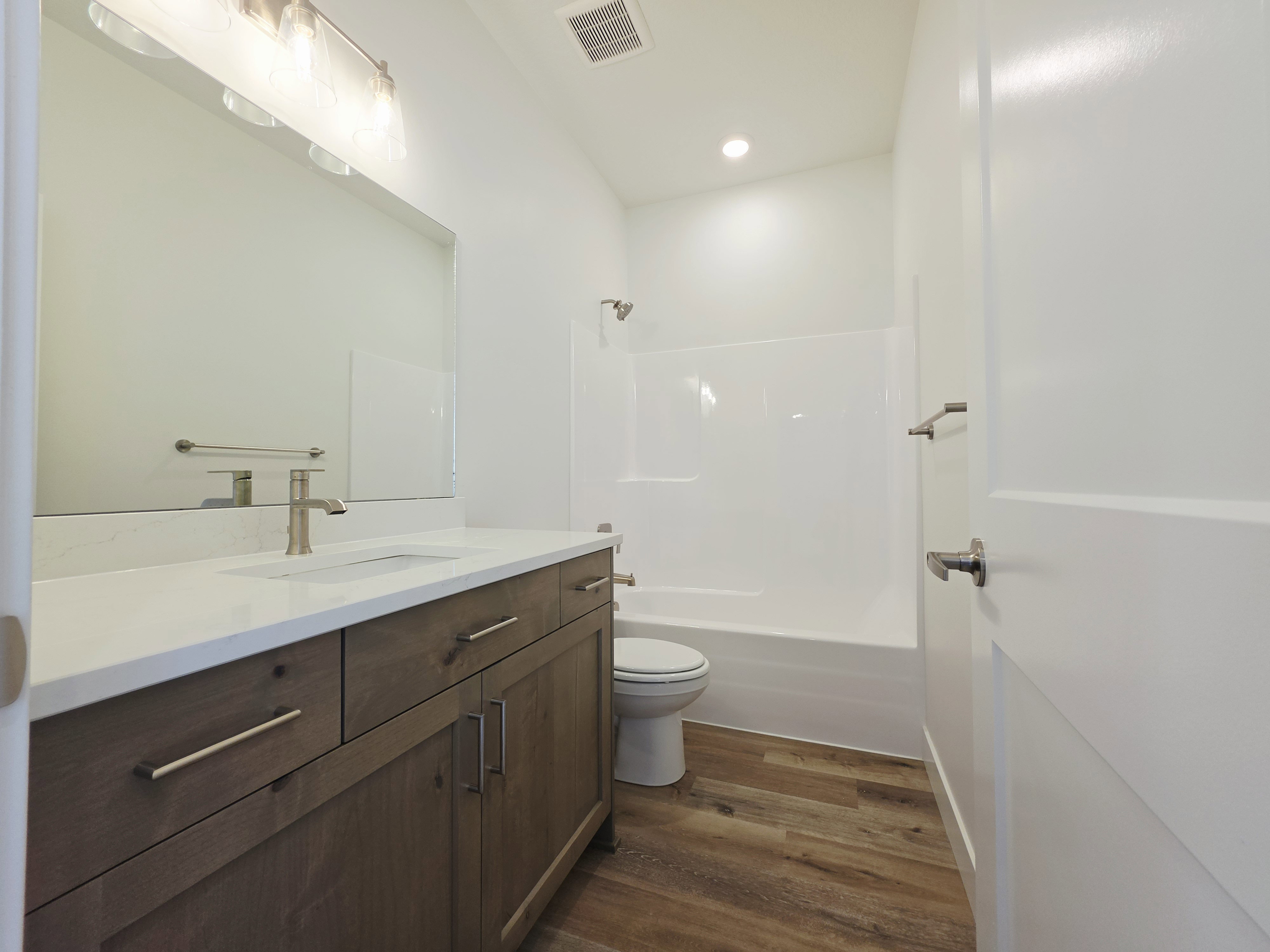 Bathroom featuring a wood-finish vanity with a light-toned countertop and an undermount sink