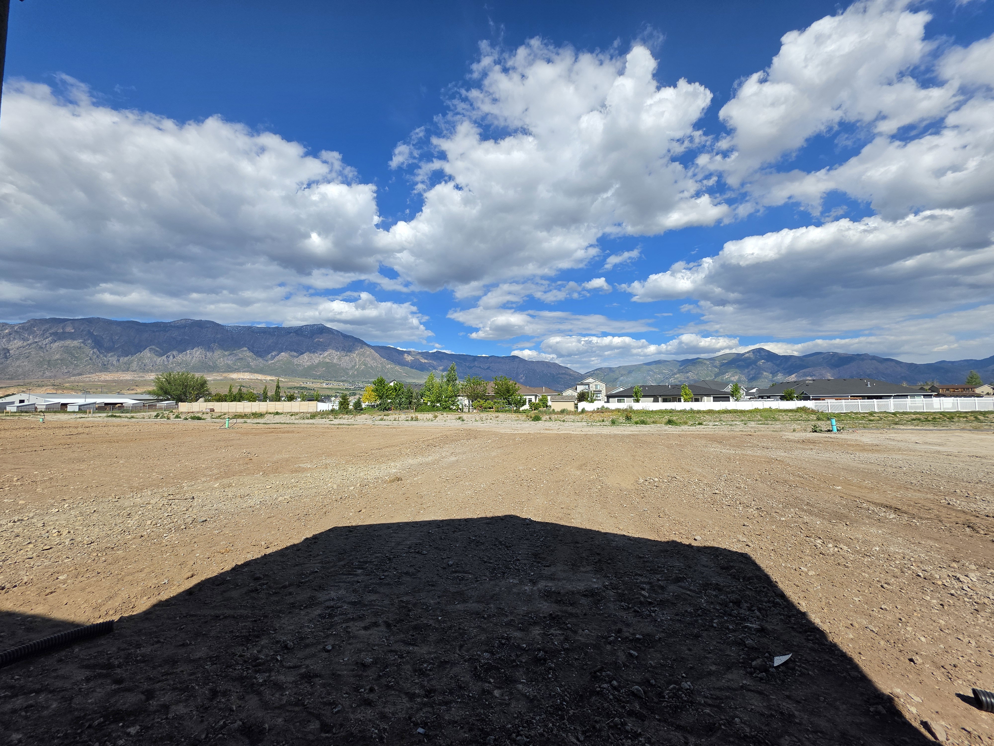 Expansive lot with a mountain backdrop, featuring a level graded surface and surrounding residential structures