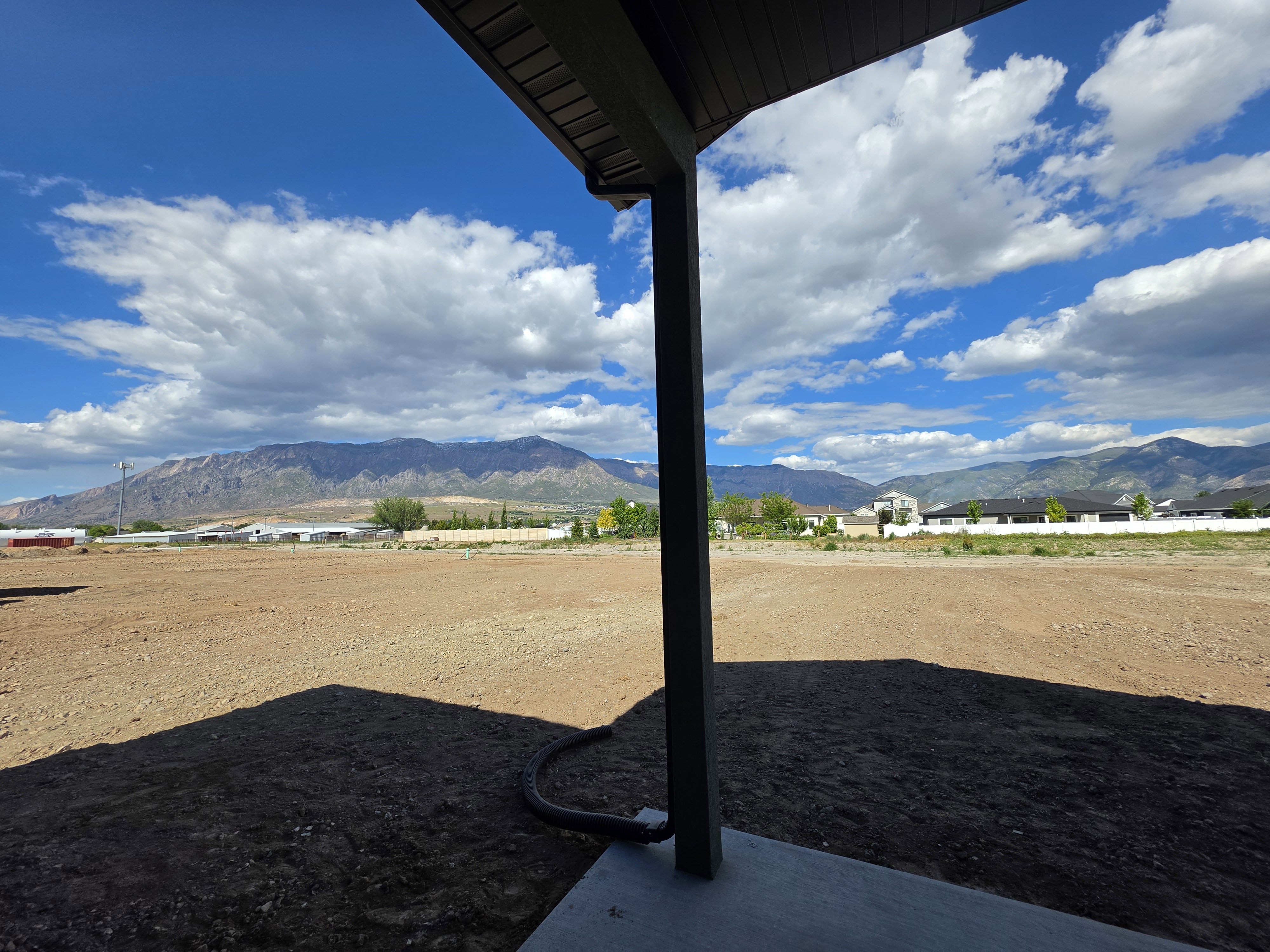 Expansive undeveloped land with a mountain backdrop, featuring a concrete patio base and structural support column