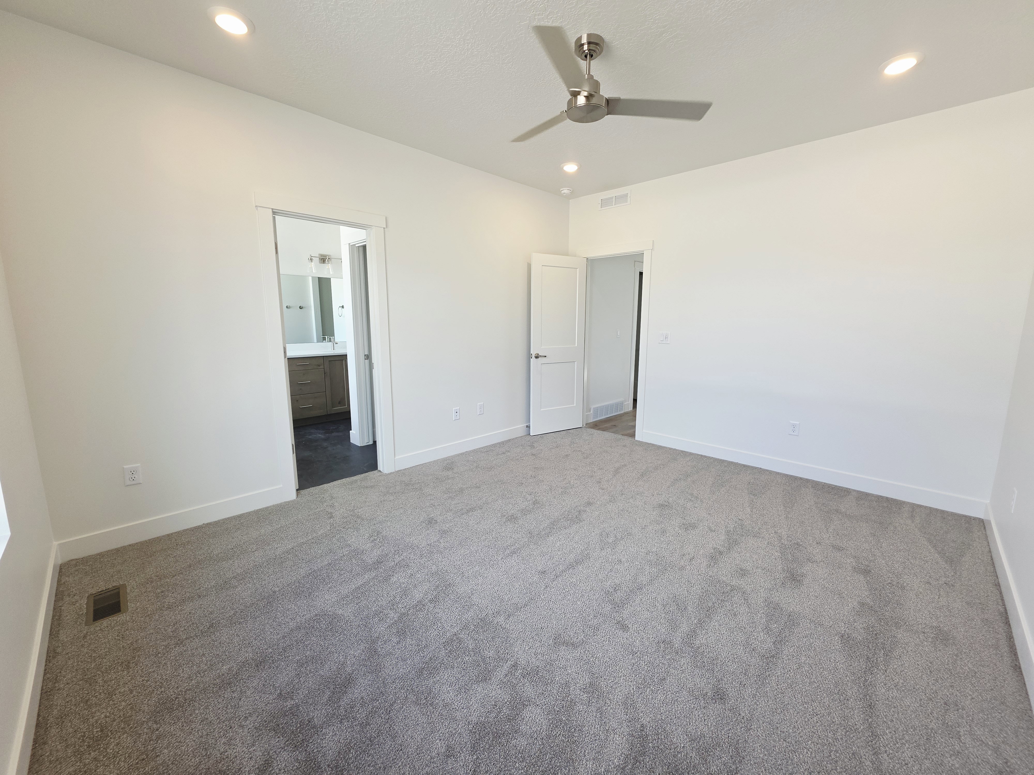 Spacious room featuring plush gray carpeting and white painted walls