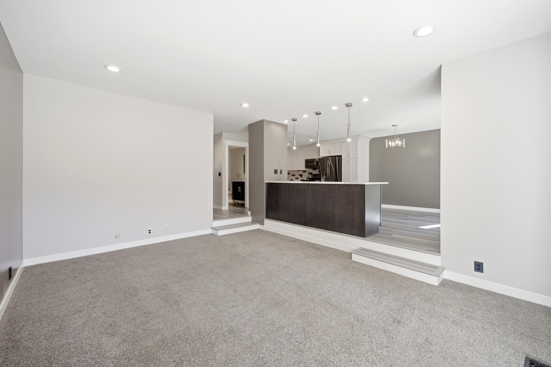 Spacious living area featuring light gray carpeting and recessed lighting
