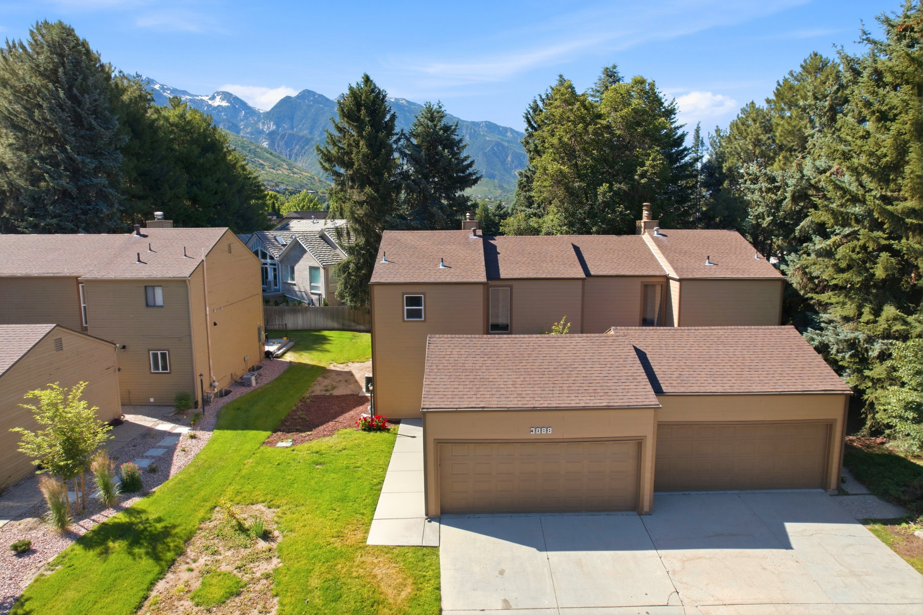 Townhome exterior featuring earth-toned siding, attached garages, and a paved driveway