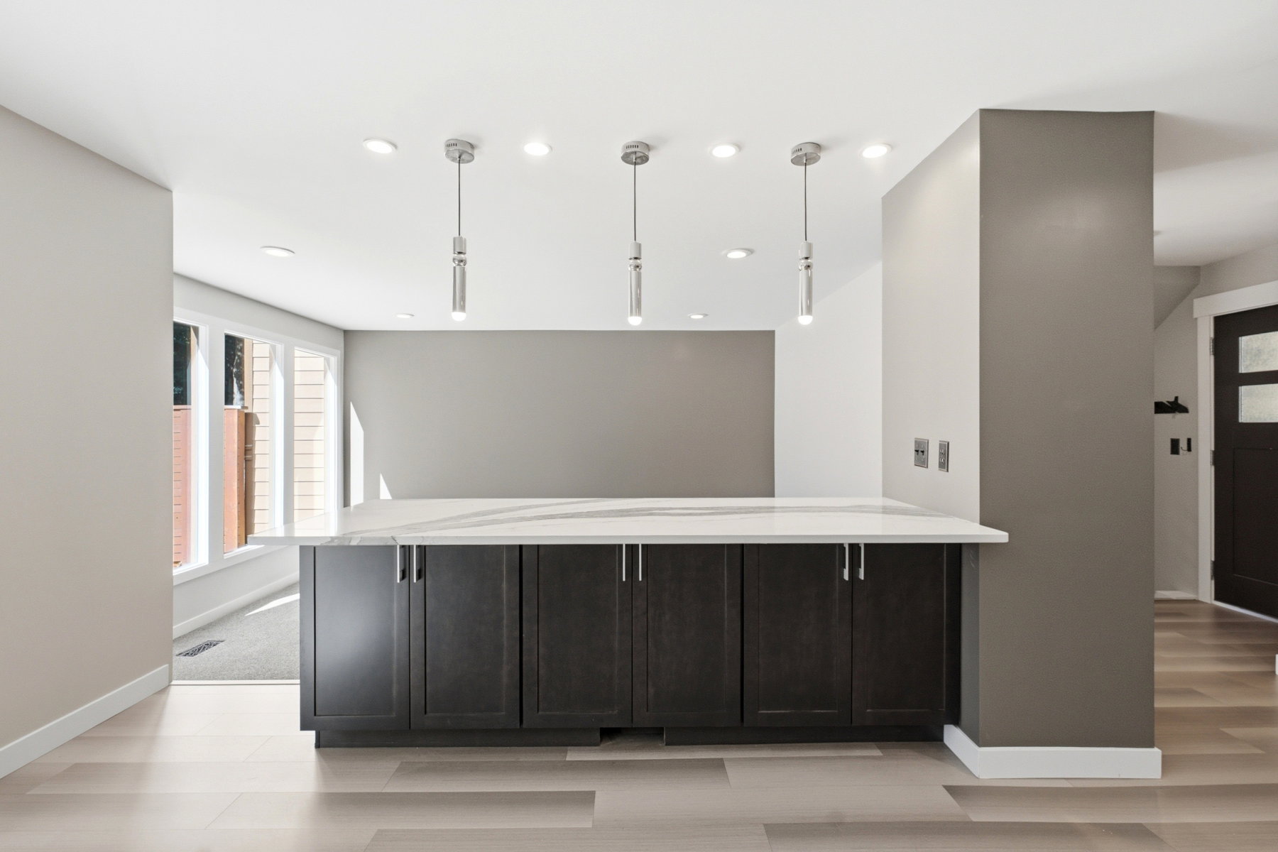 Kitchen island with dark wood-finish cabinetry, a light-colored countertop, and three pendant lights