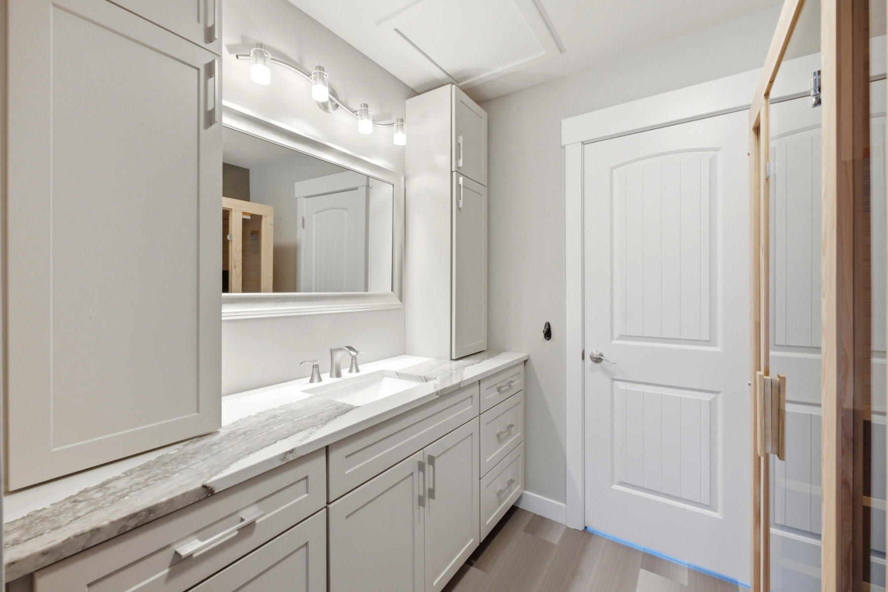 Bathroom featuring a single vanity with an undermount sink, a stone-finish countertop, white cabinetry, and wood-finish flooring